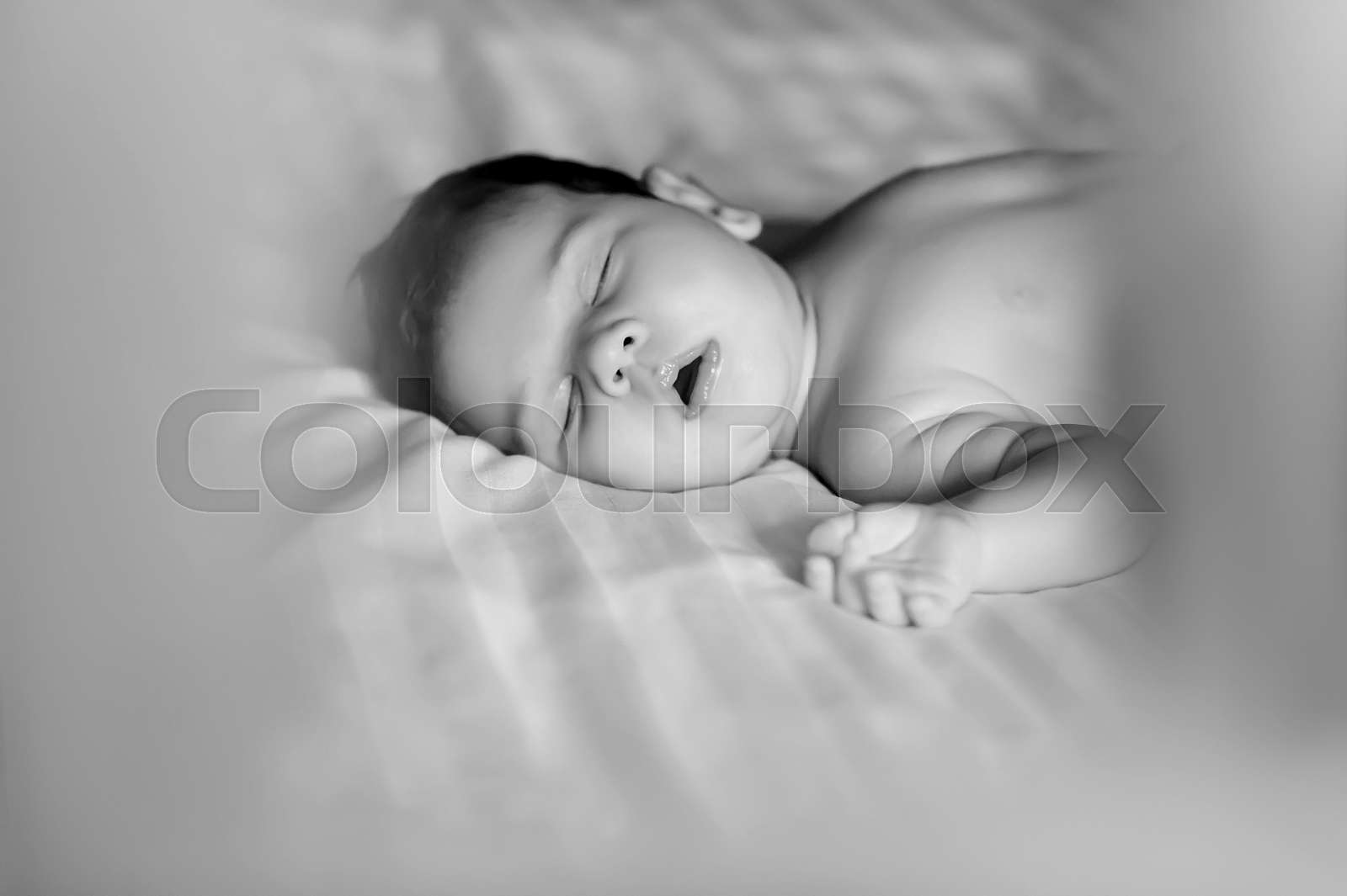 black and white picture of cute little baby boy sleeping in bed at home