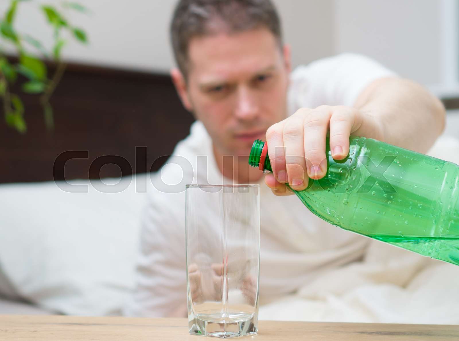 Man drinking mineral water and suffering from hangover. Stock image