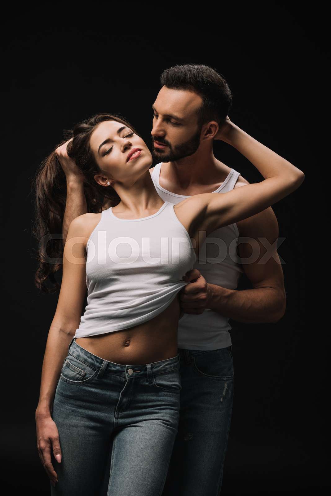 passionate man undressing girl in white singlet isolated on black