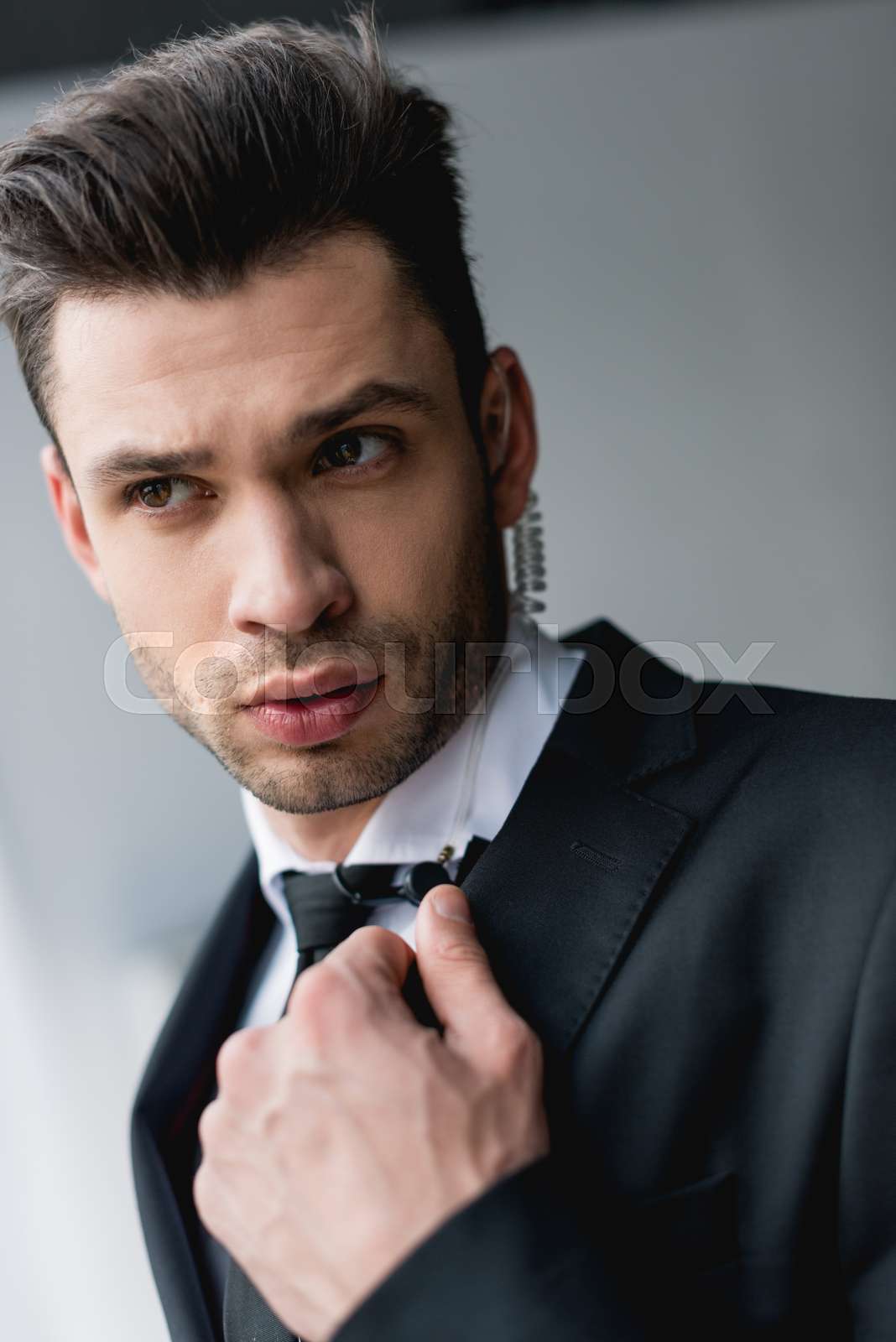 Focused bodyguard in suit using microphone stock image colourbox