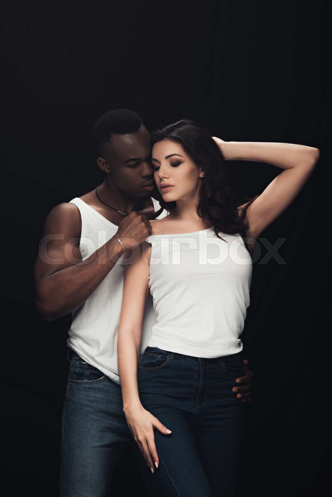 handsome african american man undressing beautiful sensual woman isolated  on black | Stock image | Colourbox