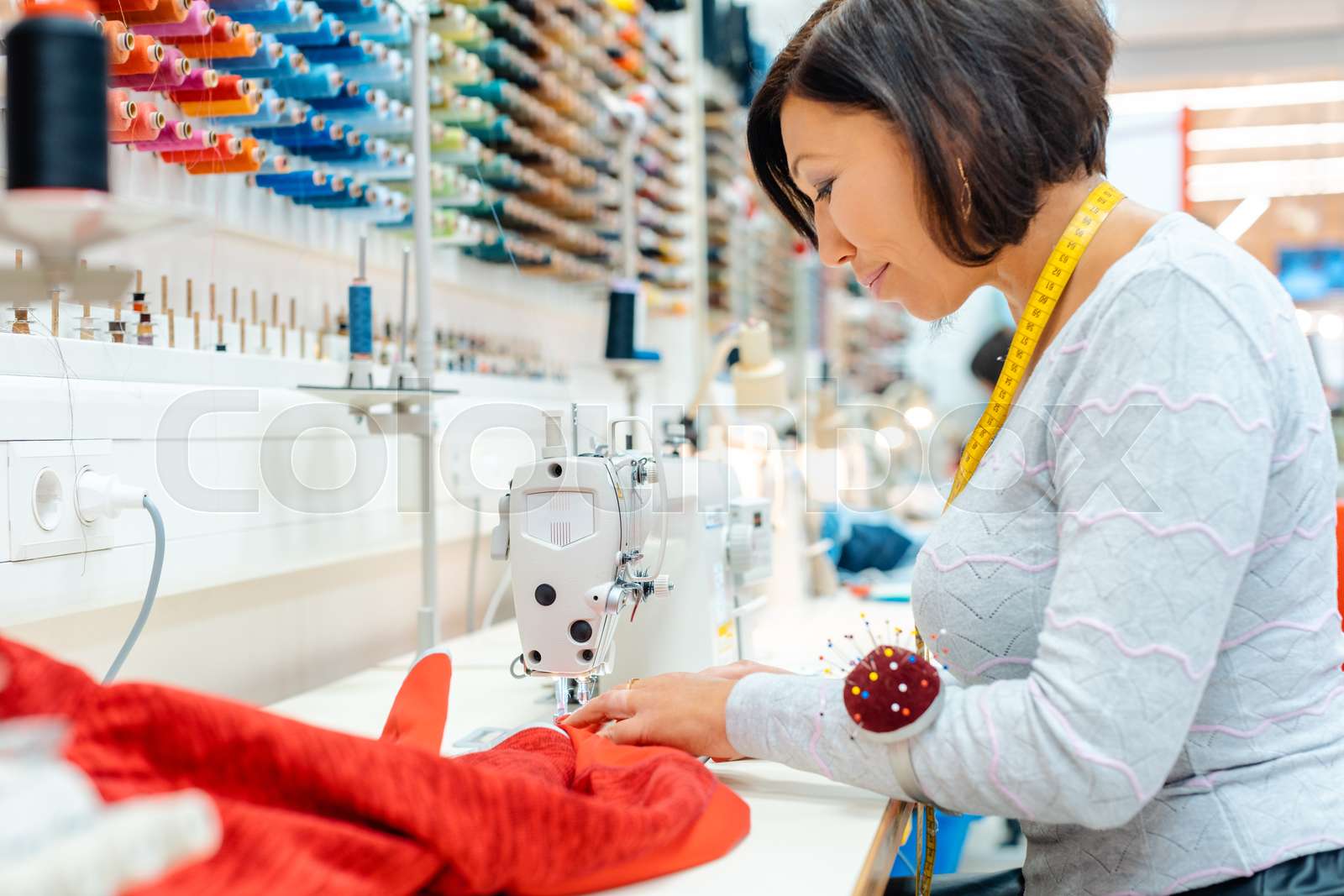 Seamstress working in her studio sewing clothes Stock image Colourbox