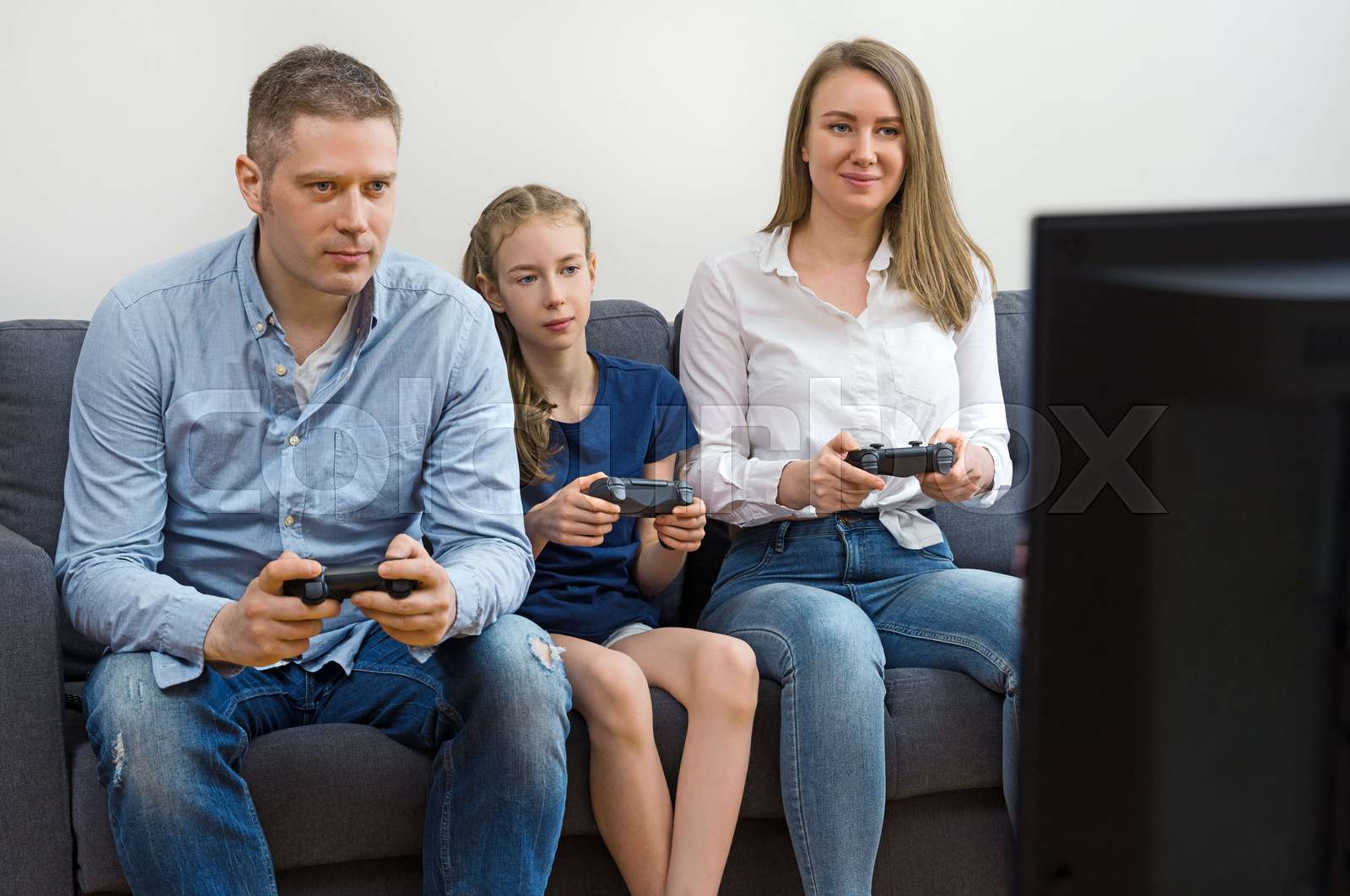 Mom, Dad and their daughter playing video game at home. | Stock image ...