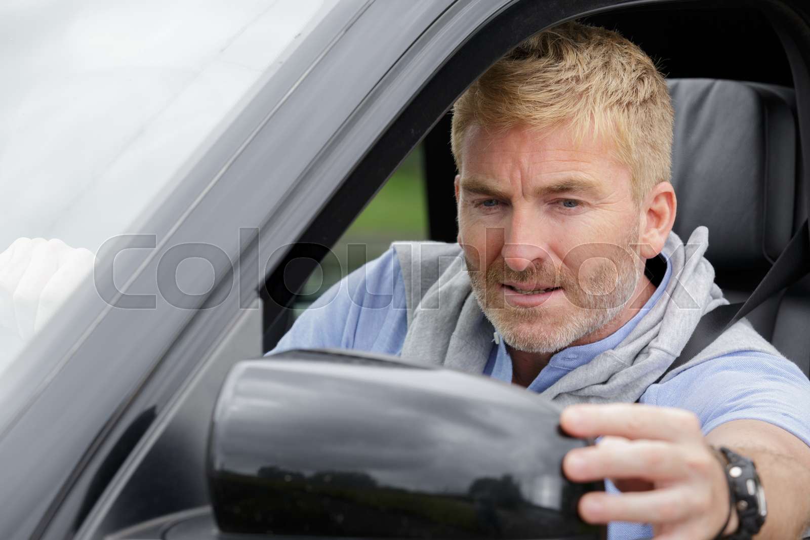 male driver adjusting side view mirror Stock image Colourbox
