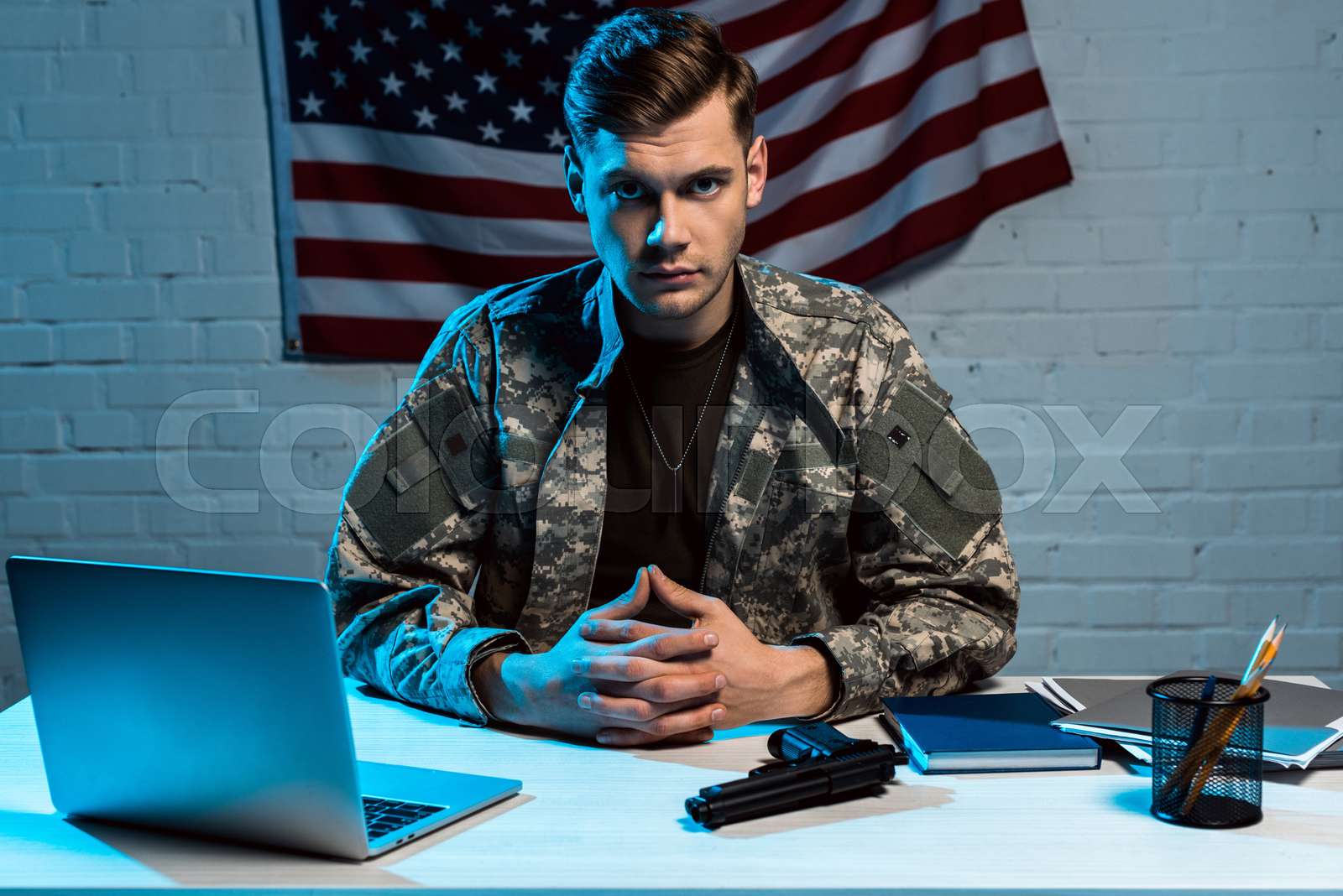 handsome military man in uniform sitting in office and looking at ...