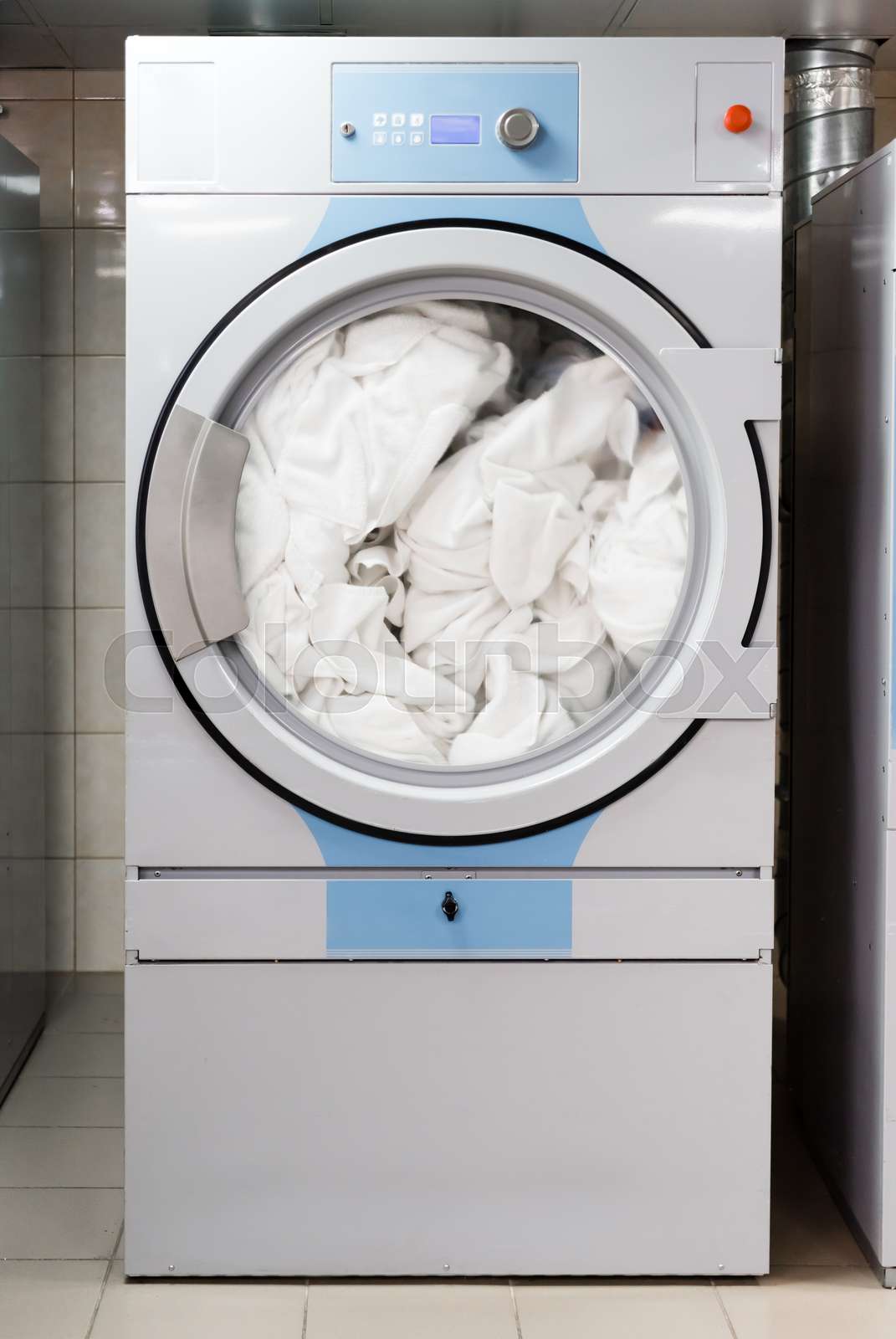 white bed sheets in electric washing machine in laundry in hotel