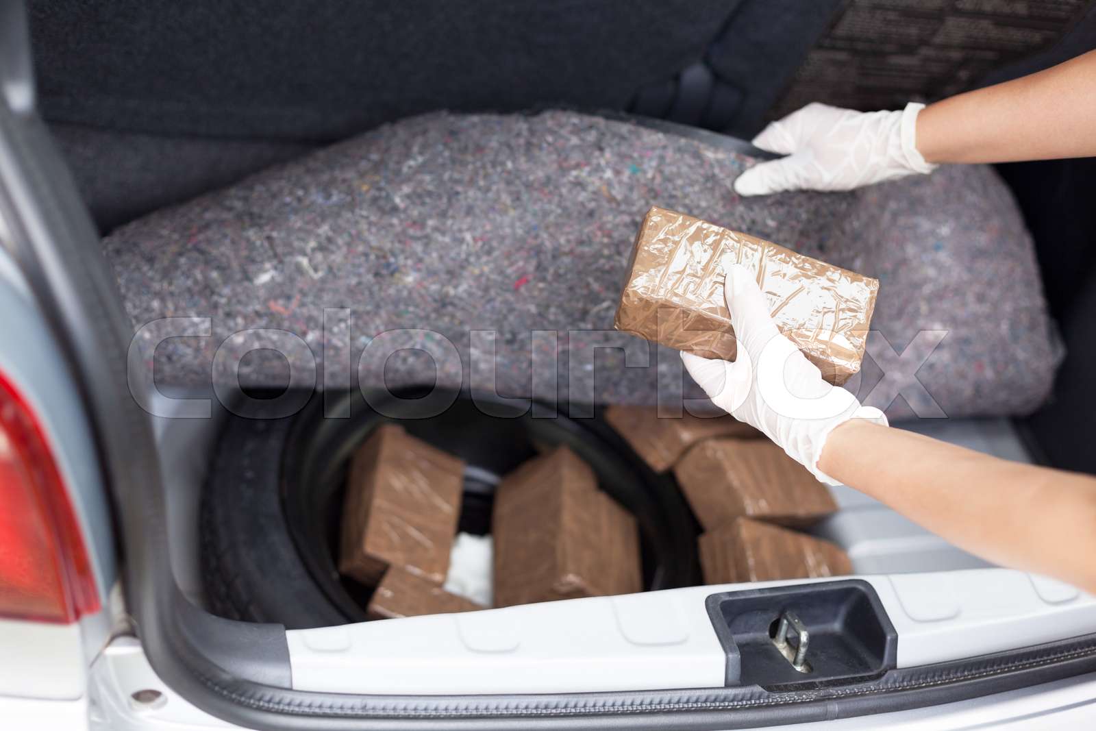 Police officer holding drug package discovered in the trunk of a car