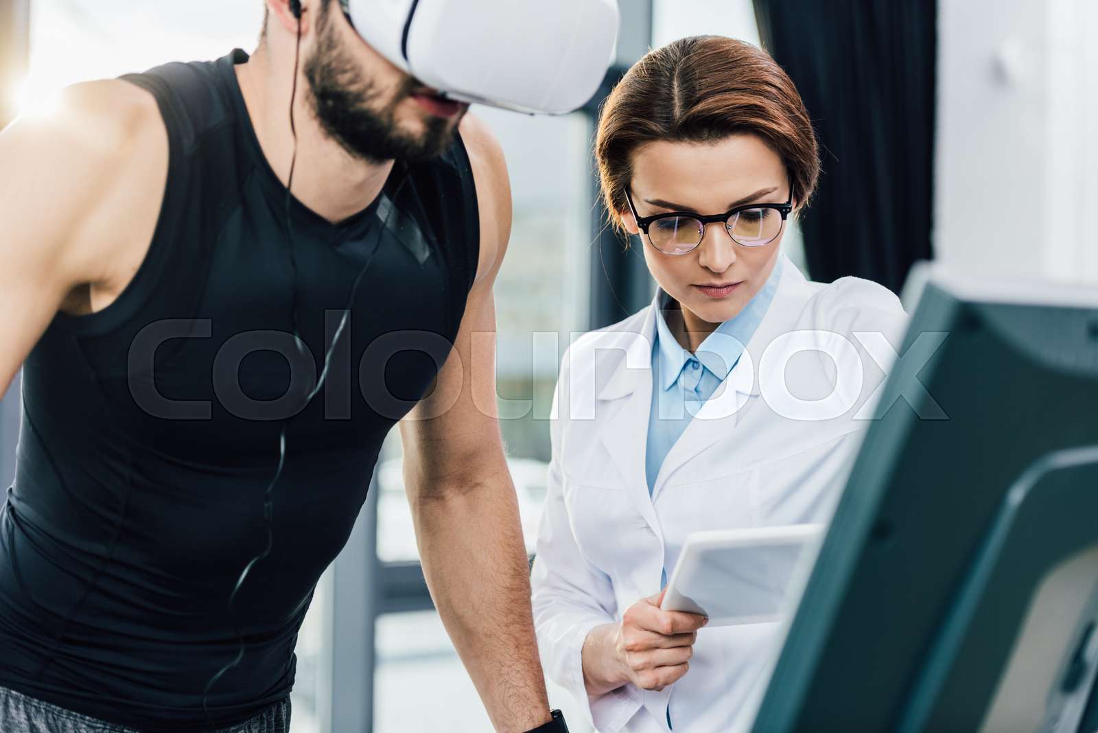 Sportsman Running On Treadmill Near Doctor With Digital Tablet During