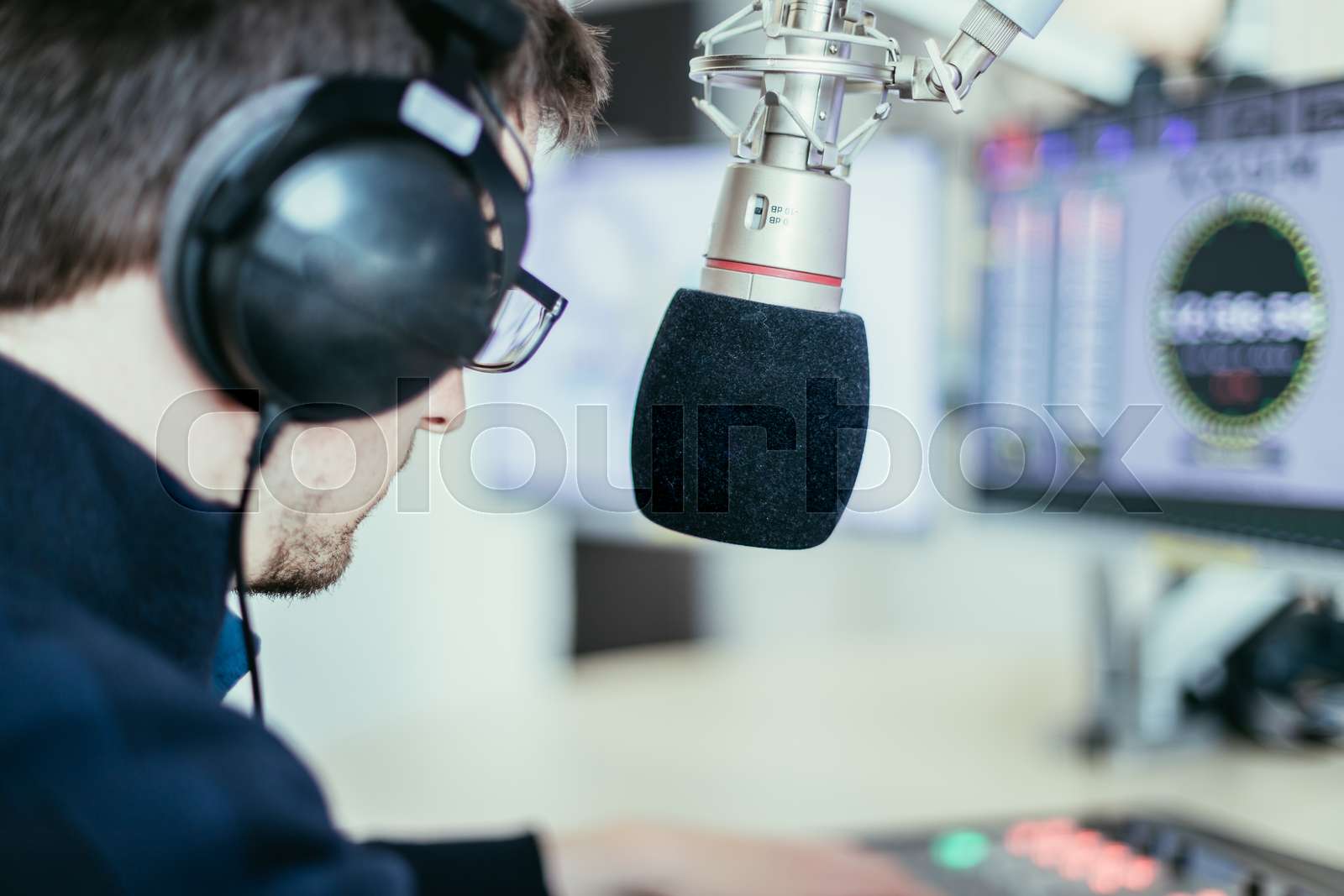 Radio moderator is sitting in a modern broadcasting studio and talking