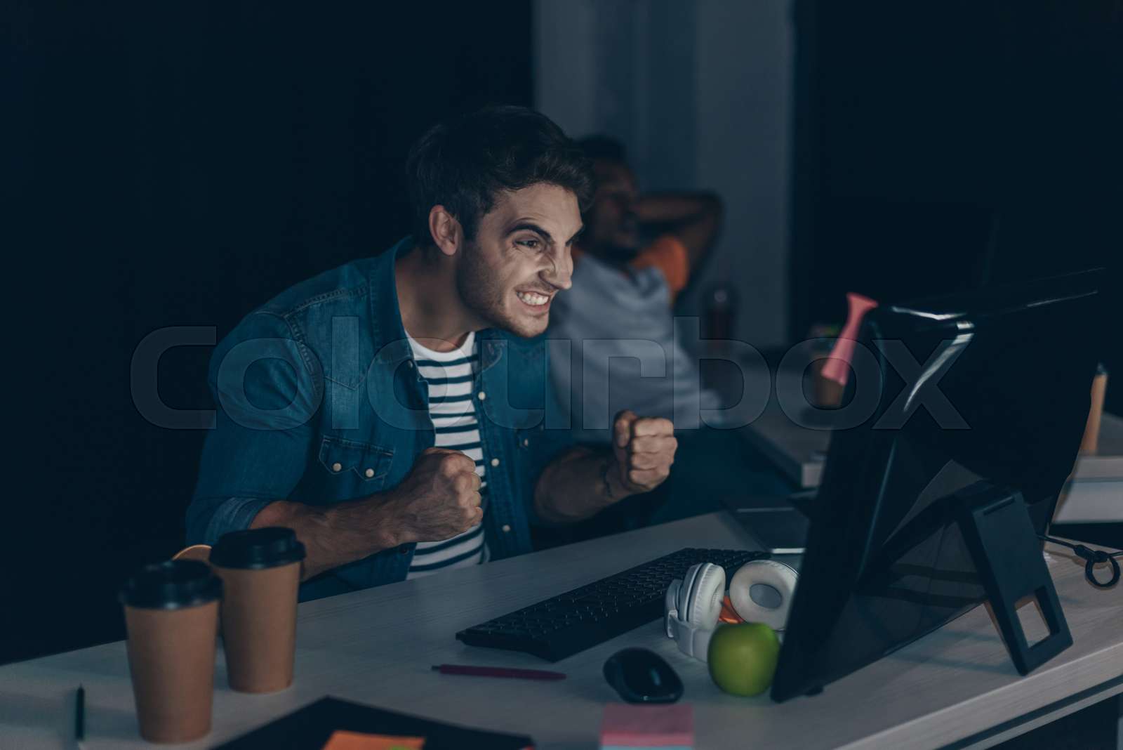 angry programmer gesturing while working at night in office near ...