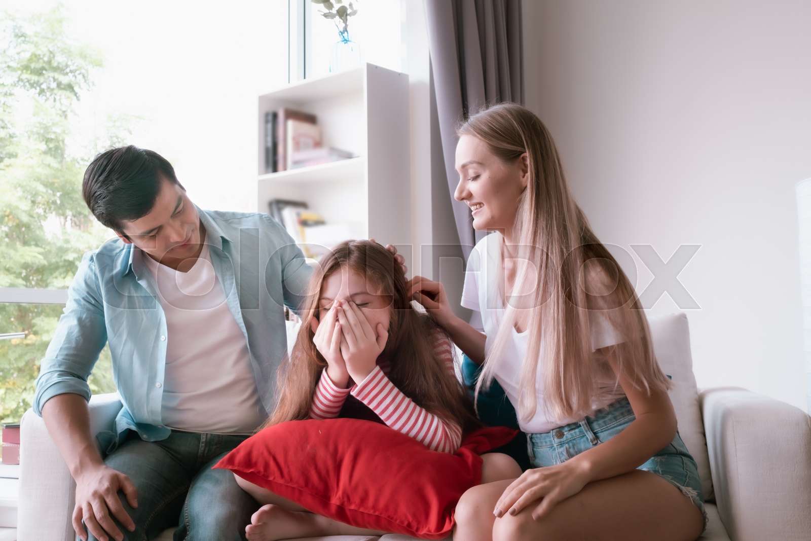 little girl sad and father and mother consoling her at home together ...