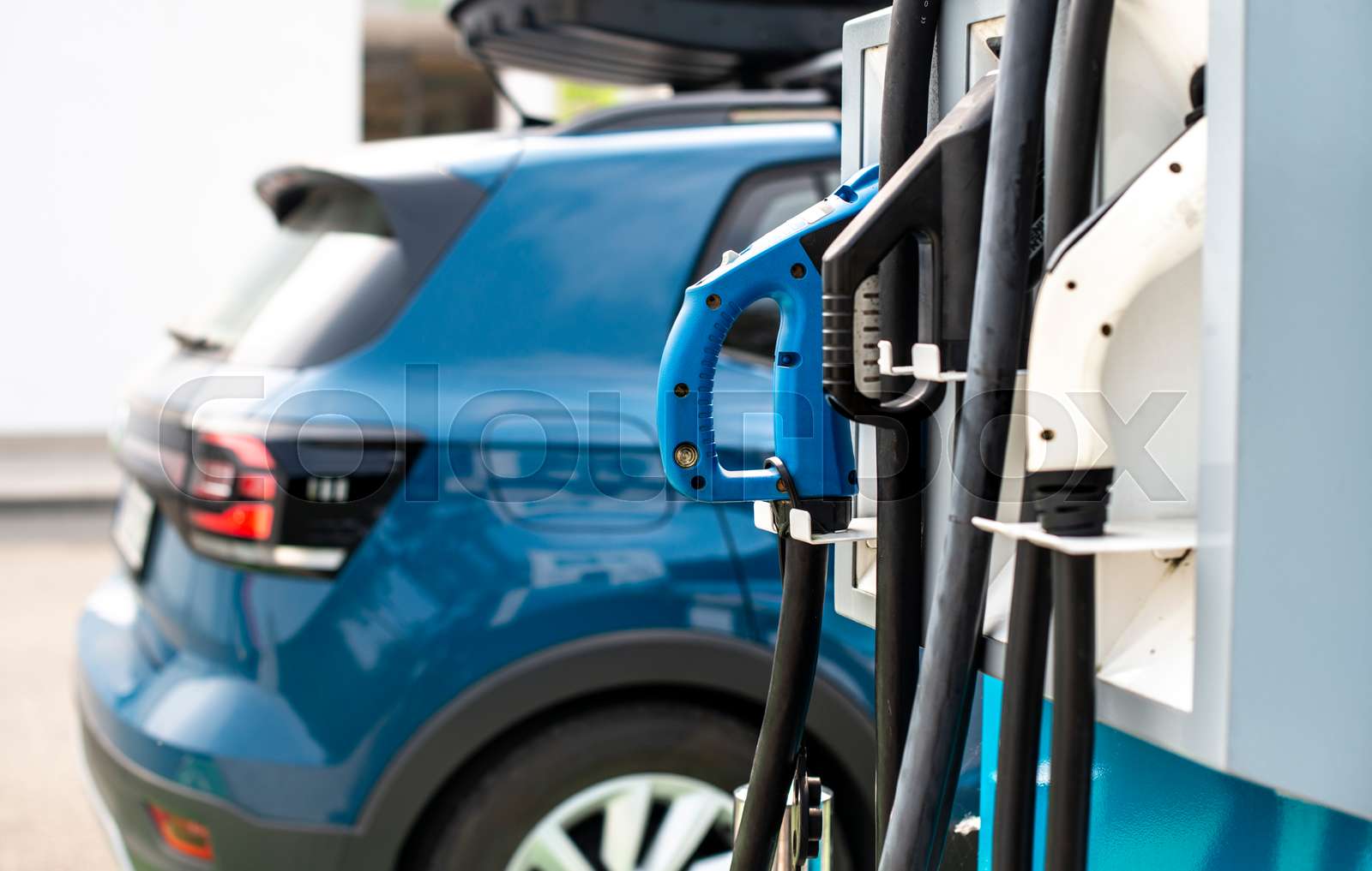 Electric car on gas station. Blue car and electric plug for charging