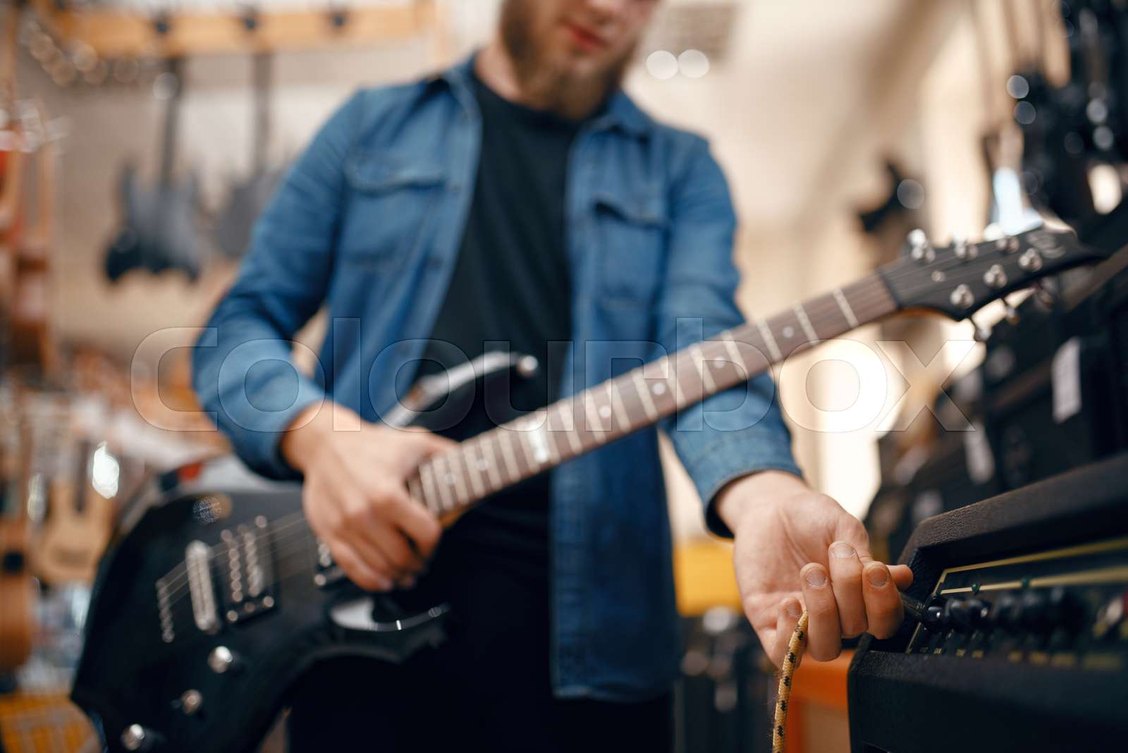 Guitarist plays on electric guitar in music store Stock image Colourbox