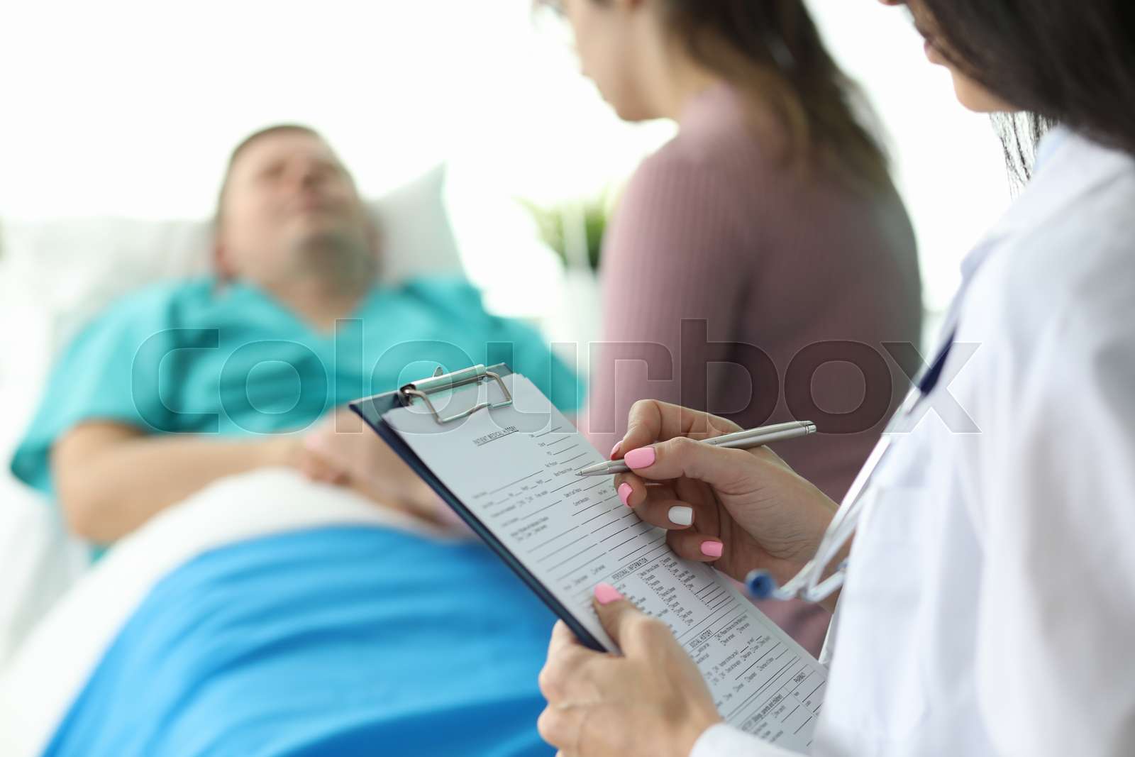 Doctor filling form about condition of patient | Stock image | Colourbox