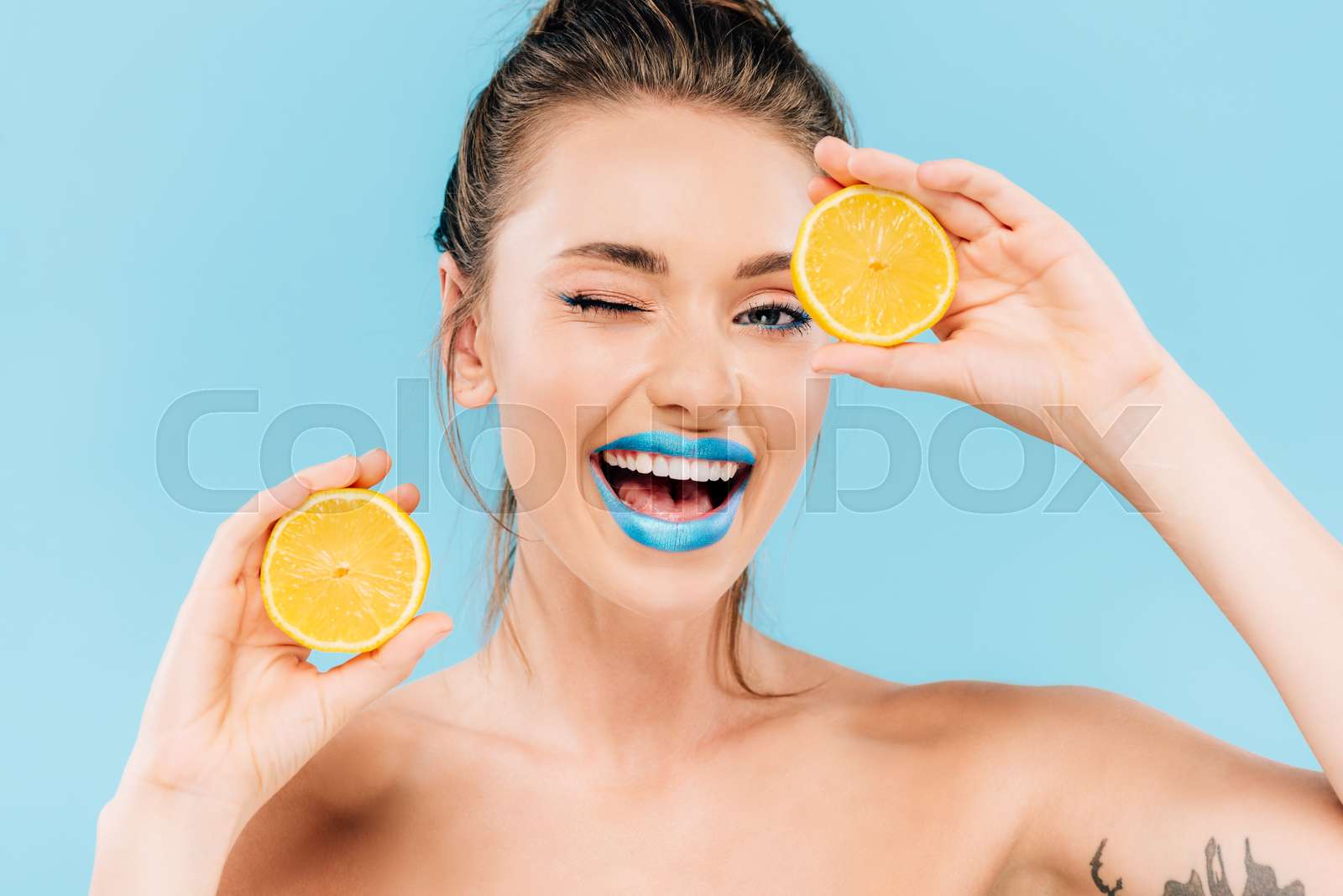 happy winking naked beautiful woman with blue lips holding orange