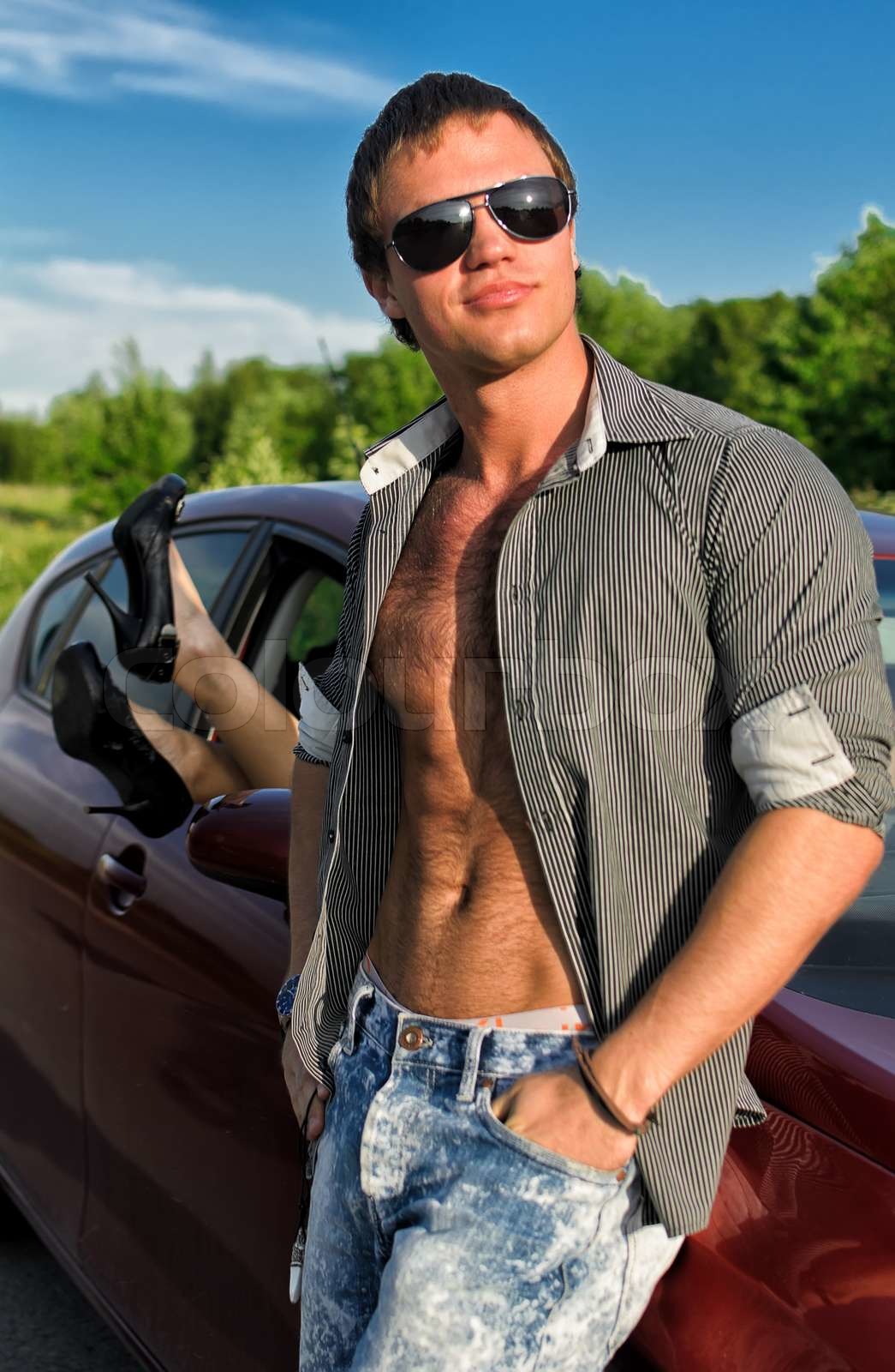 Sexy Mann posiert in der Nähe der Autos mit Frau Beine Stock aus dem ...