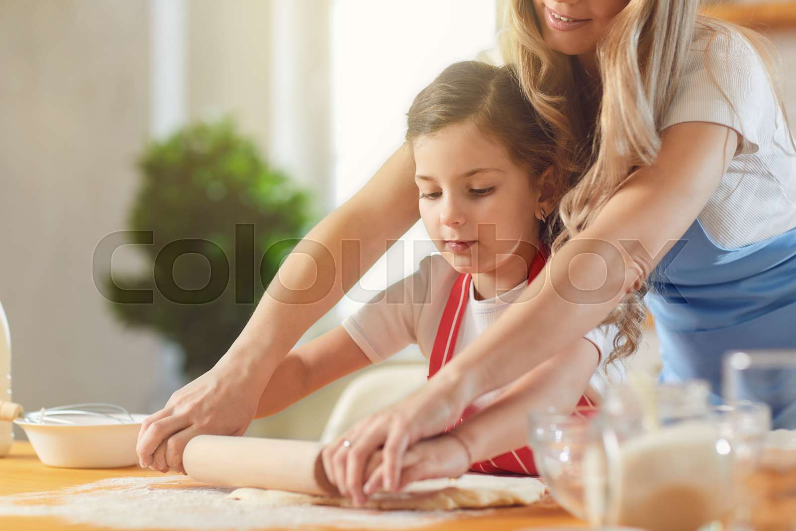 Mother And Daughter Prepare Flour Baked Goods On A Table In The Kitchen 