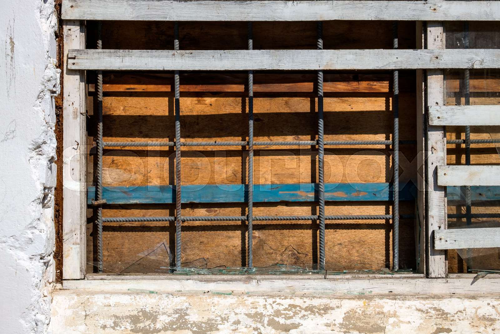 Broken window boarded up by plywood and welded with iron bars Stock