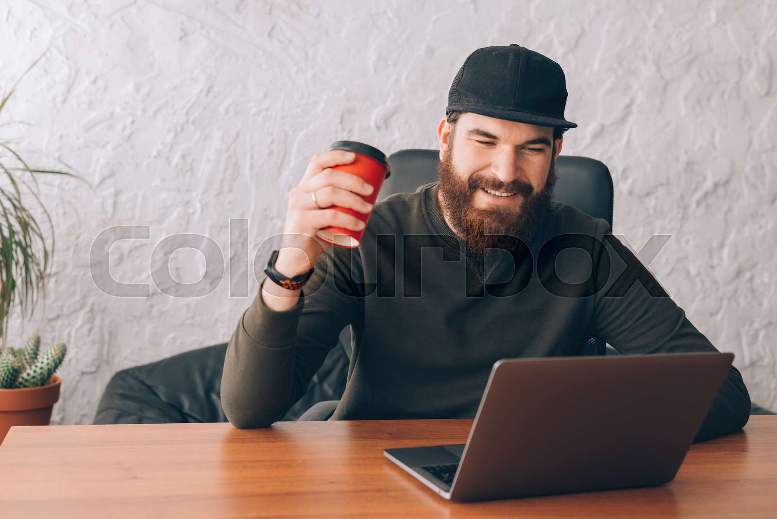 man working on laptop in office with coffee and calendar