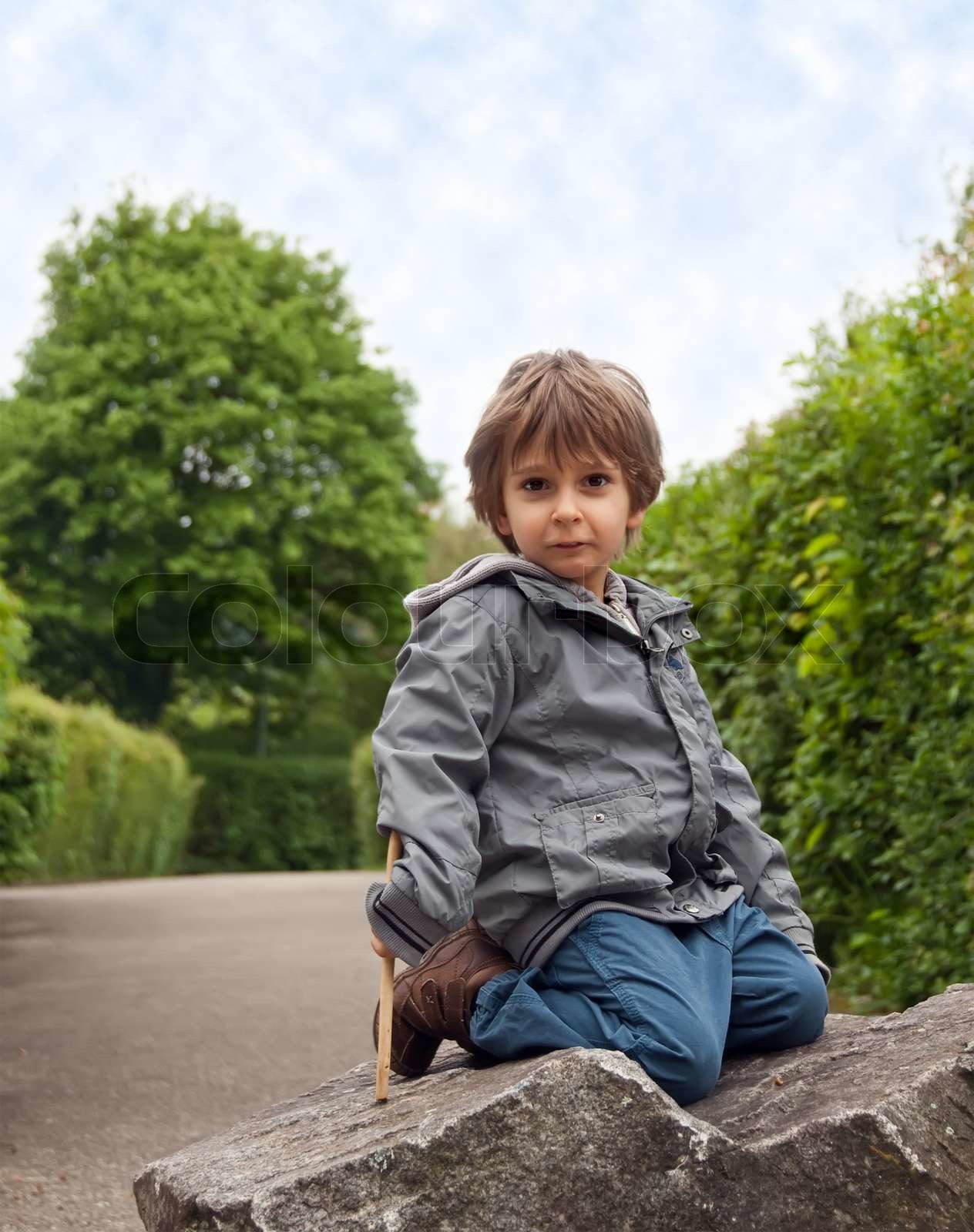 A little boy sitting on a rock. | Stock image | Colourbox