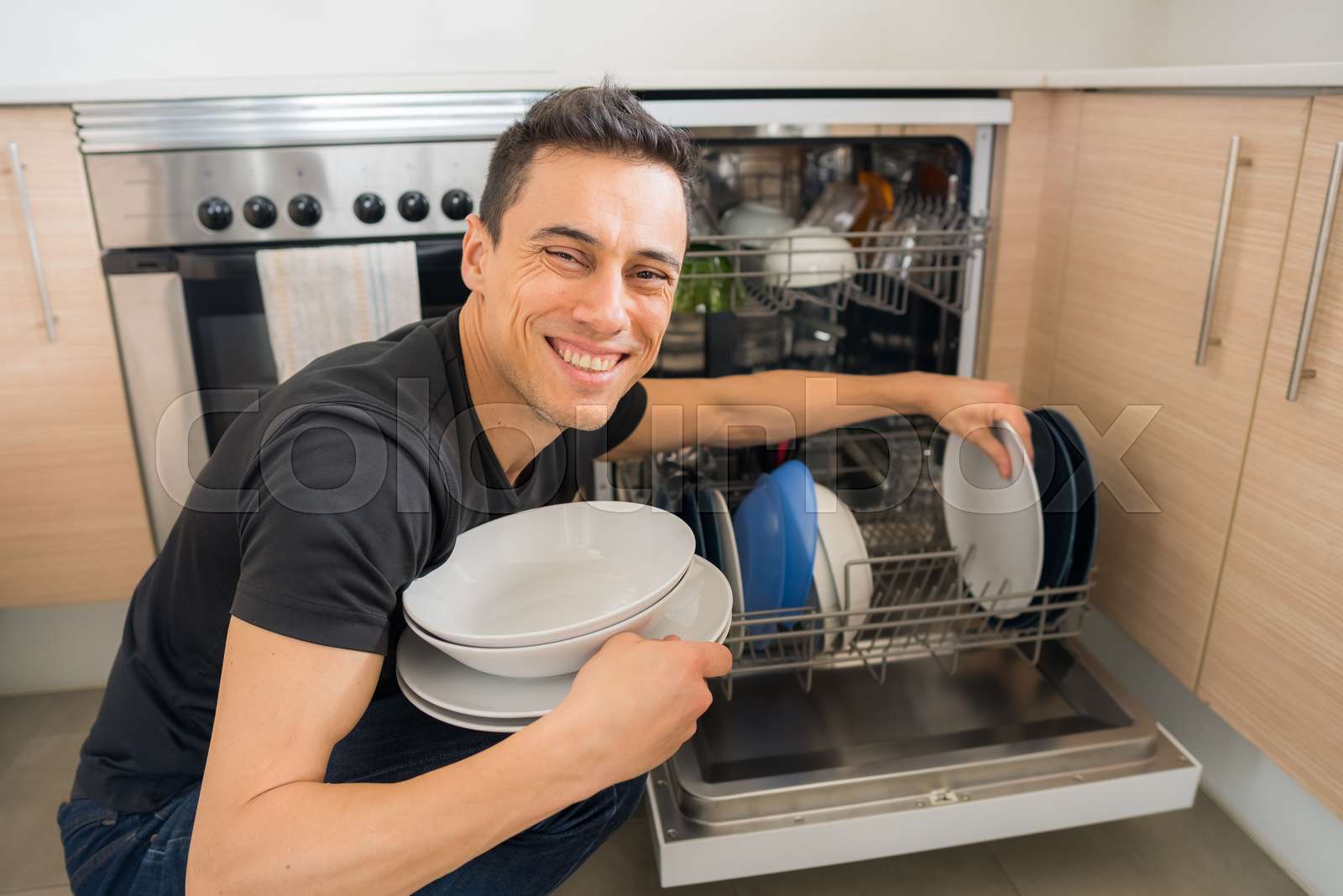 Man taking dishes out of the dishwasher. Stock image Colourbox