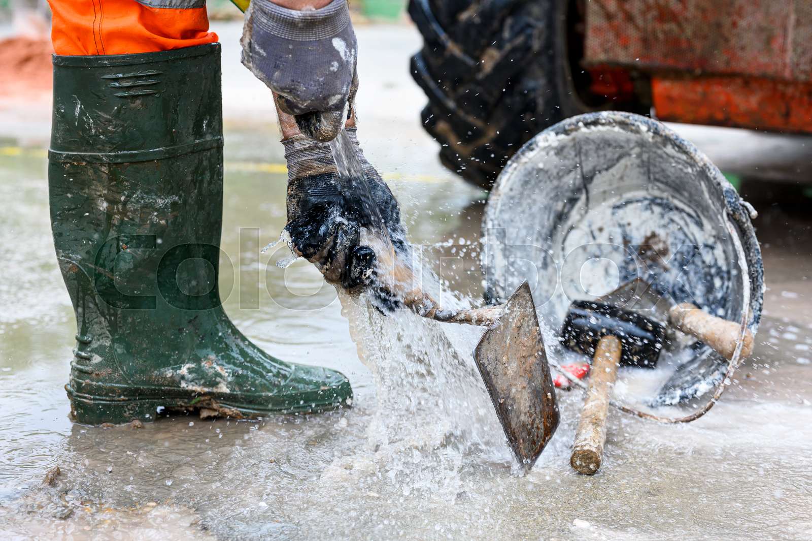Construction worker washing tools at construction site road street