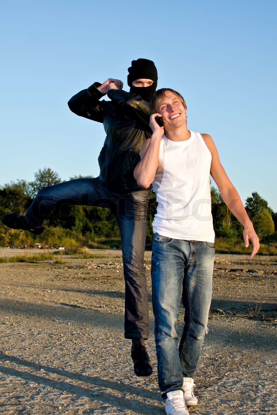 Bandit in mask trying to rob young man Stock image Colourbox