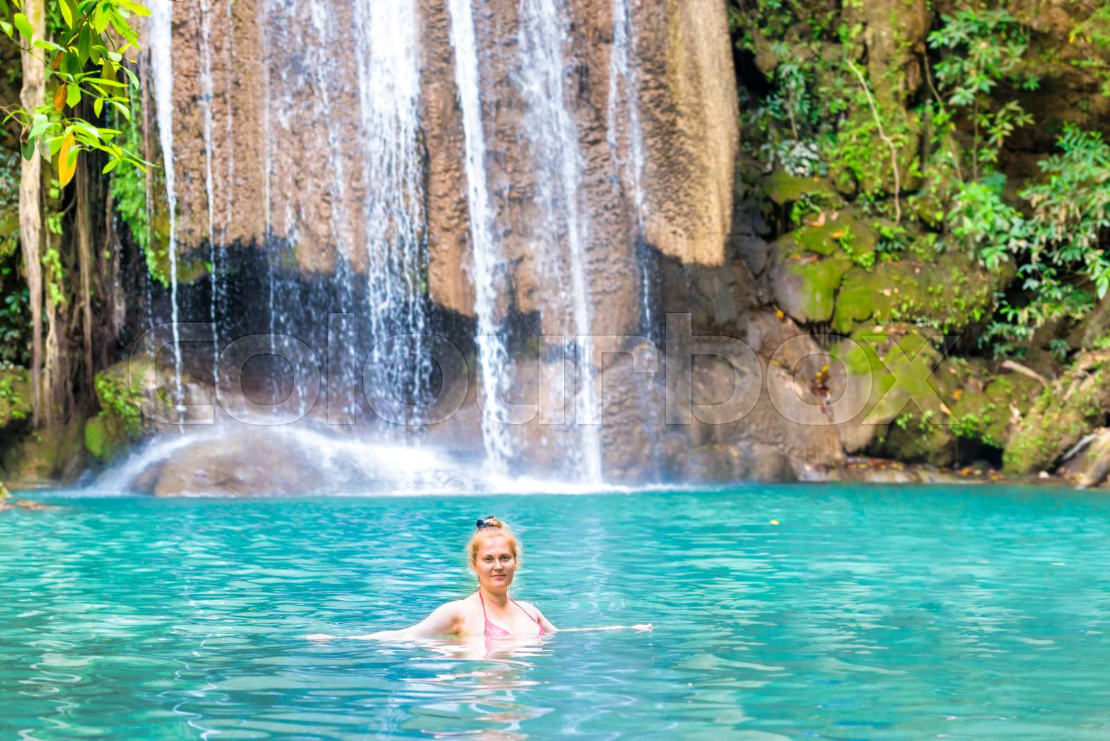 Young woman relaxes in emerald blue lake, Erawan National park