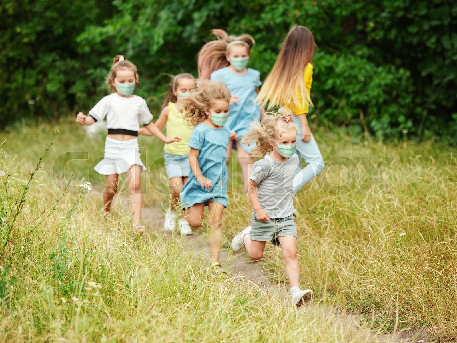 Happy little caucasian kids jumping and running on the meadow, in ...