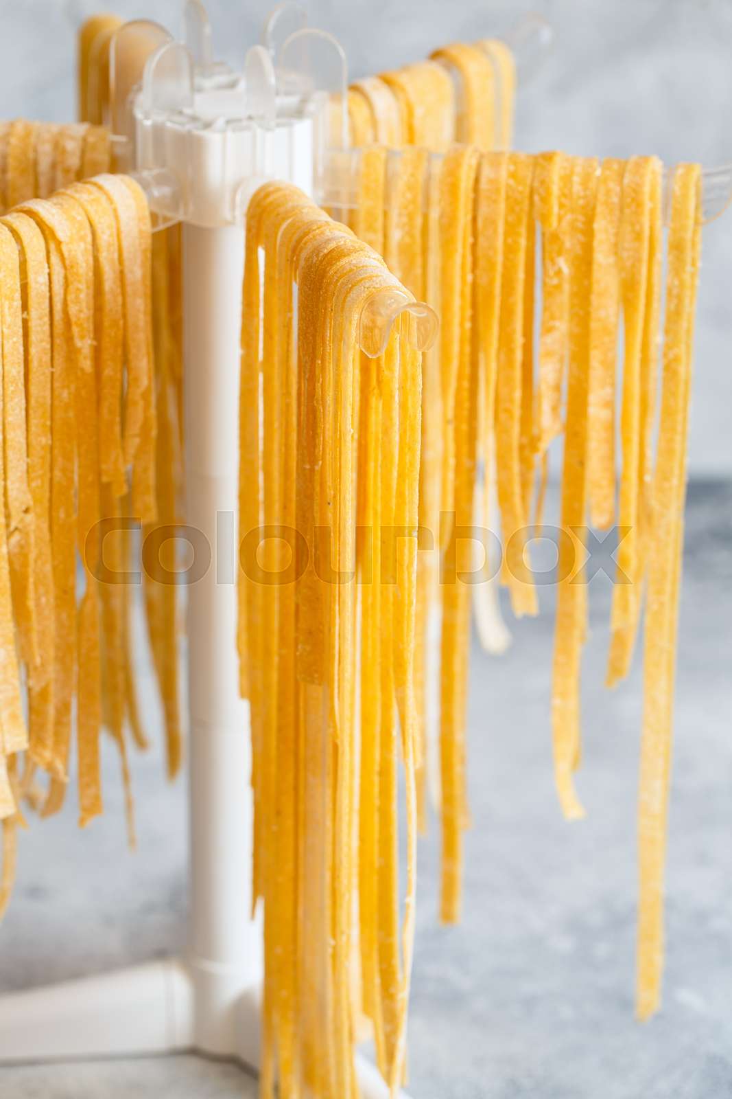 Homemade Italian tagliatelle hanging on a pasta drying rack. Fresh