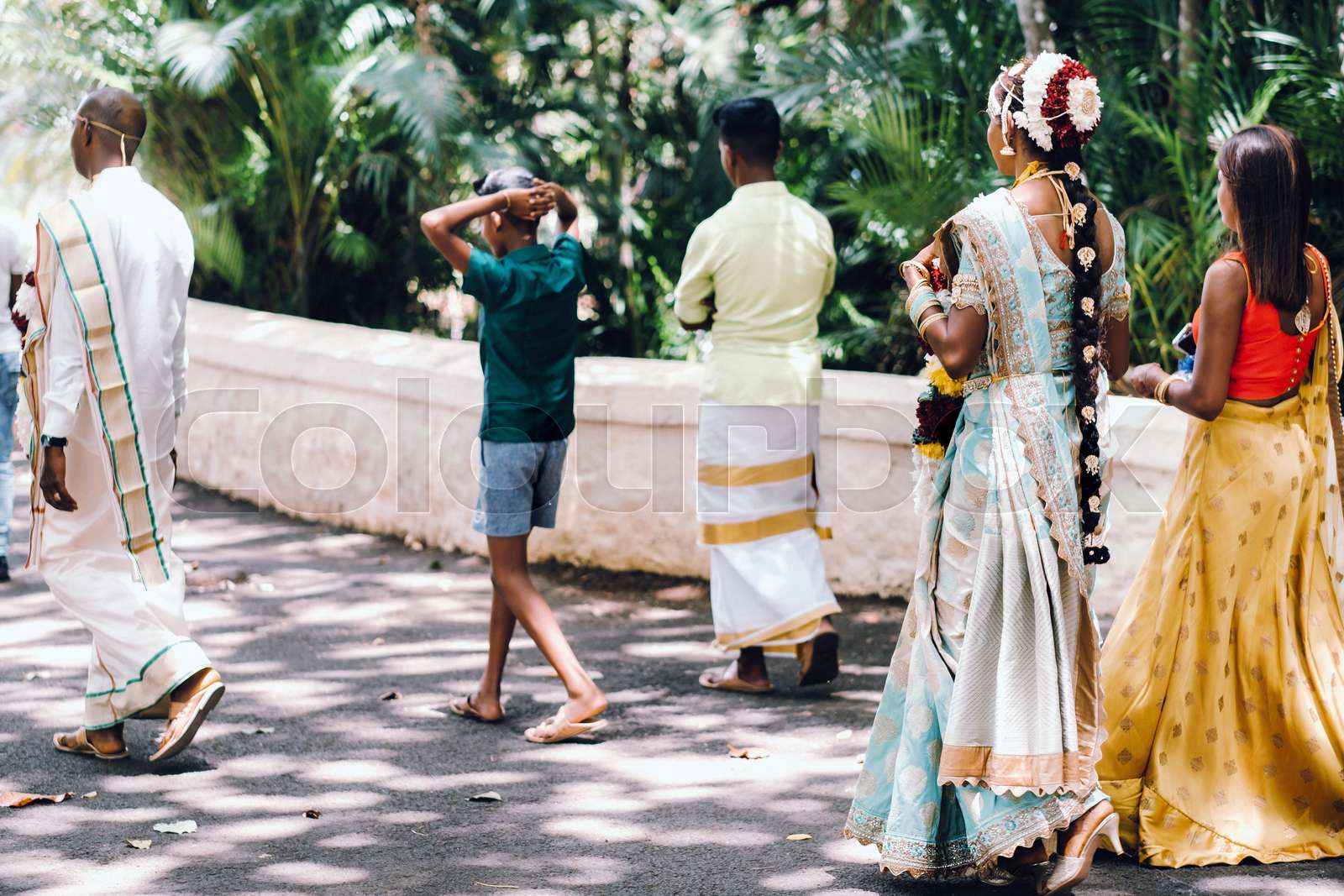 unrecognizable Locals in traditional outfits walk through the Park of