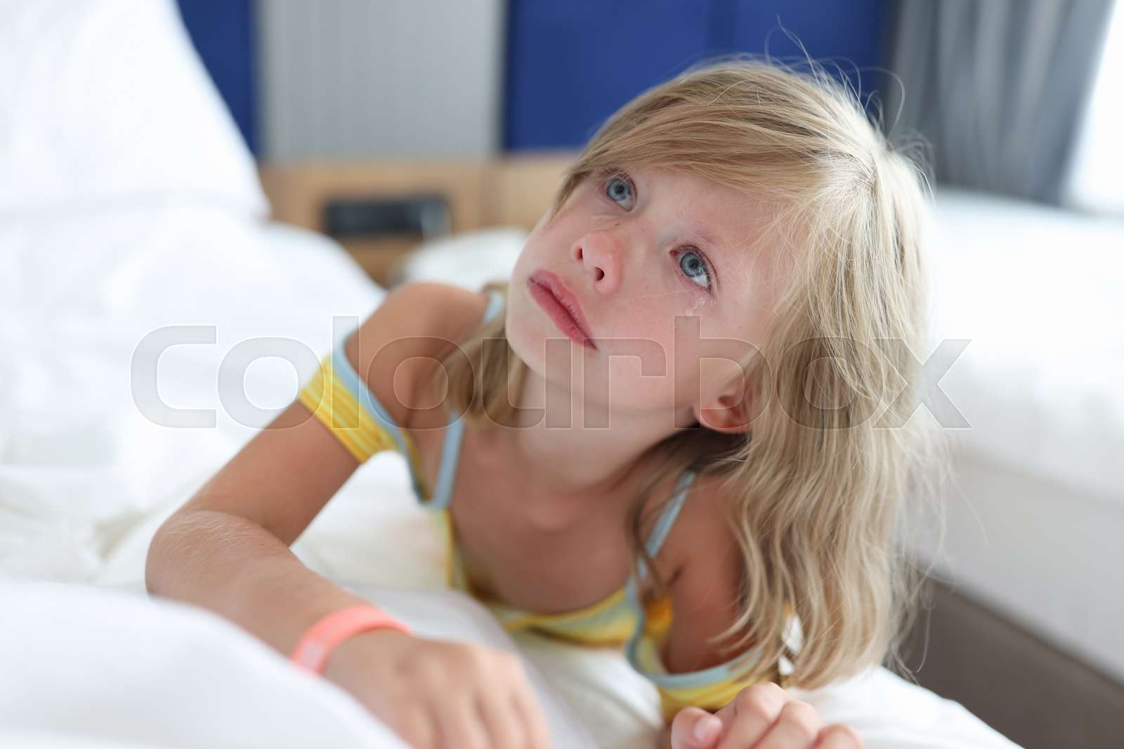 Little girl lying in bed in clinic and crying Stock image Colourbox
