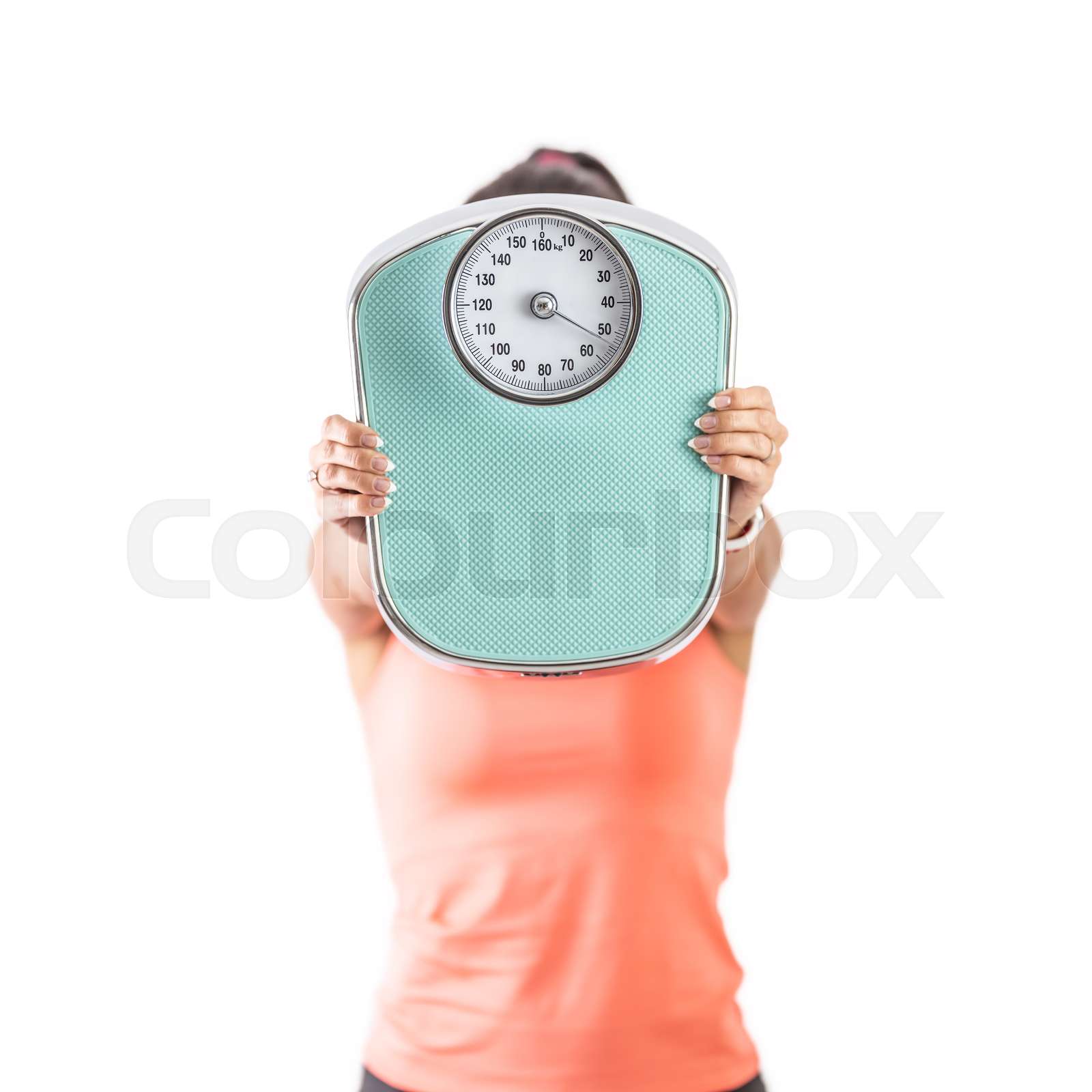 Woman holds a weighing scale against the camera covering her face with ...