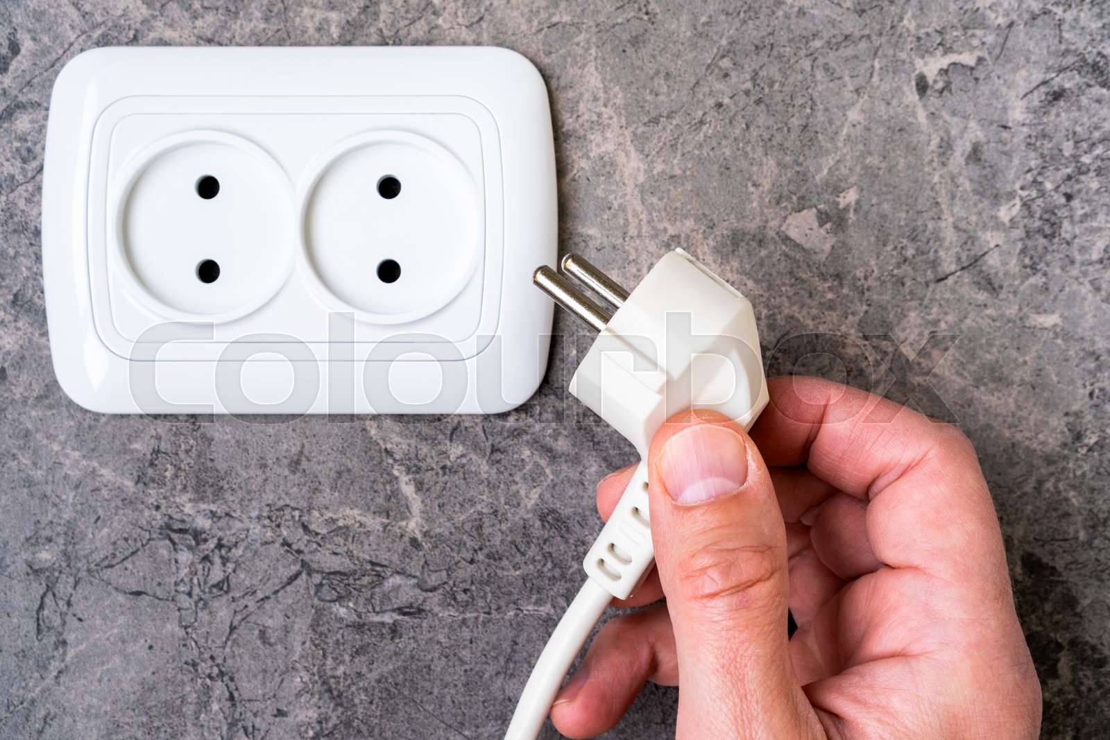 Male hand puts plug in the electric socket Stock image Colourbox