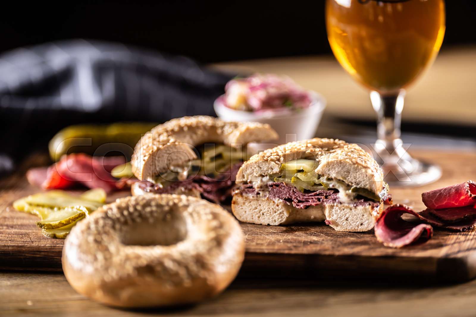 Bagel filled with juicy beef pastrami together with pickles Stock
