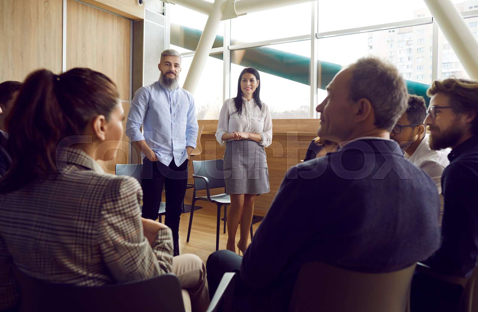 Male and female managers communicate with staff sitting around them in