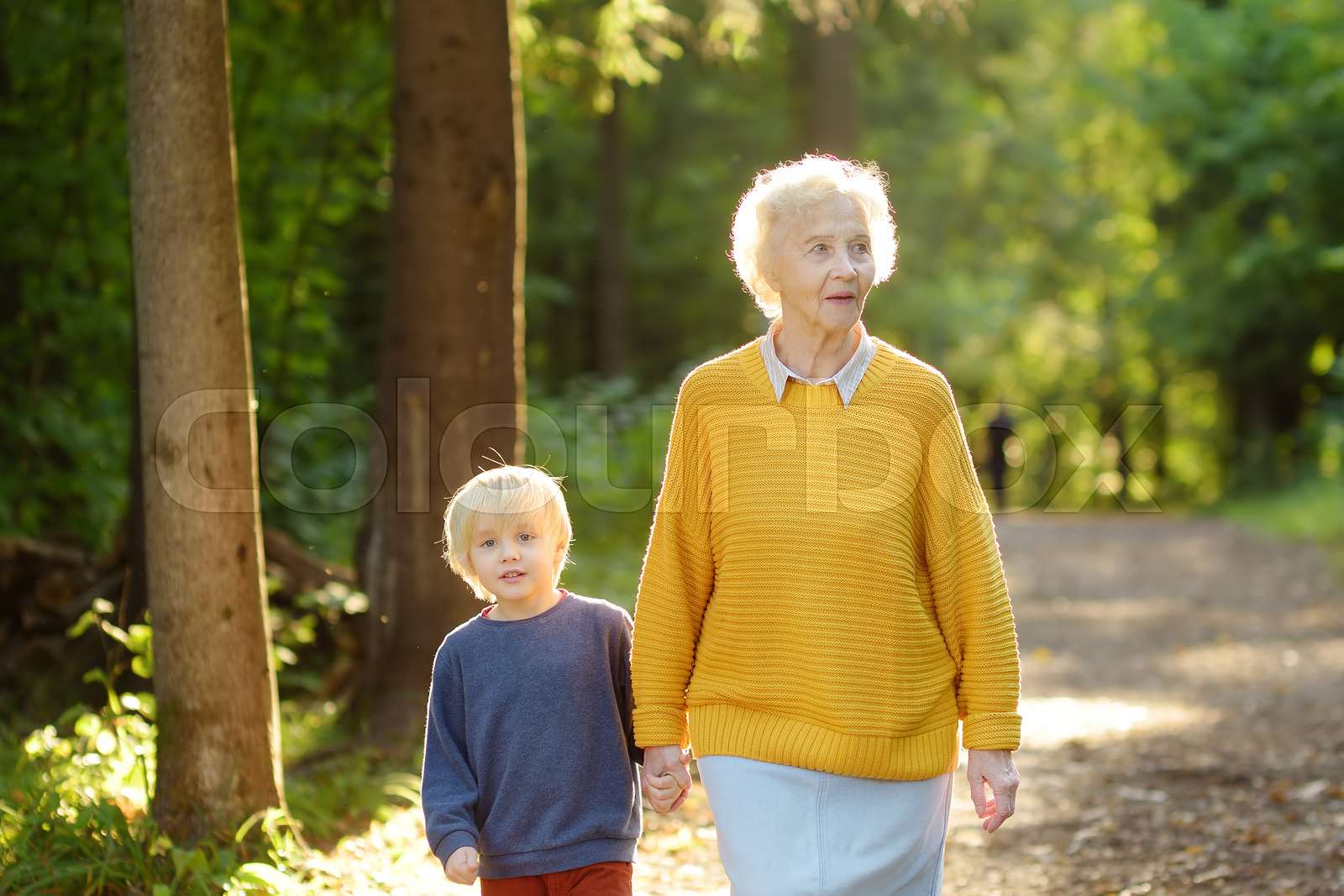 Elderly grandmother and her little grandchild walking together in sunny