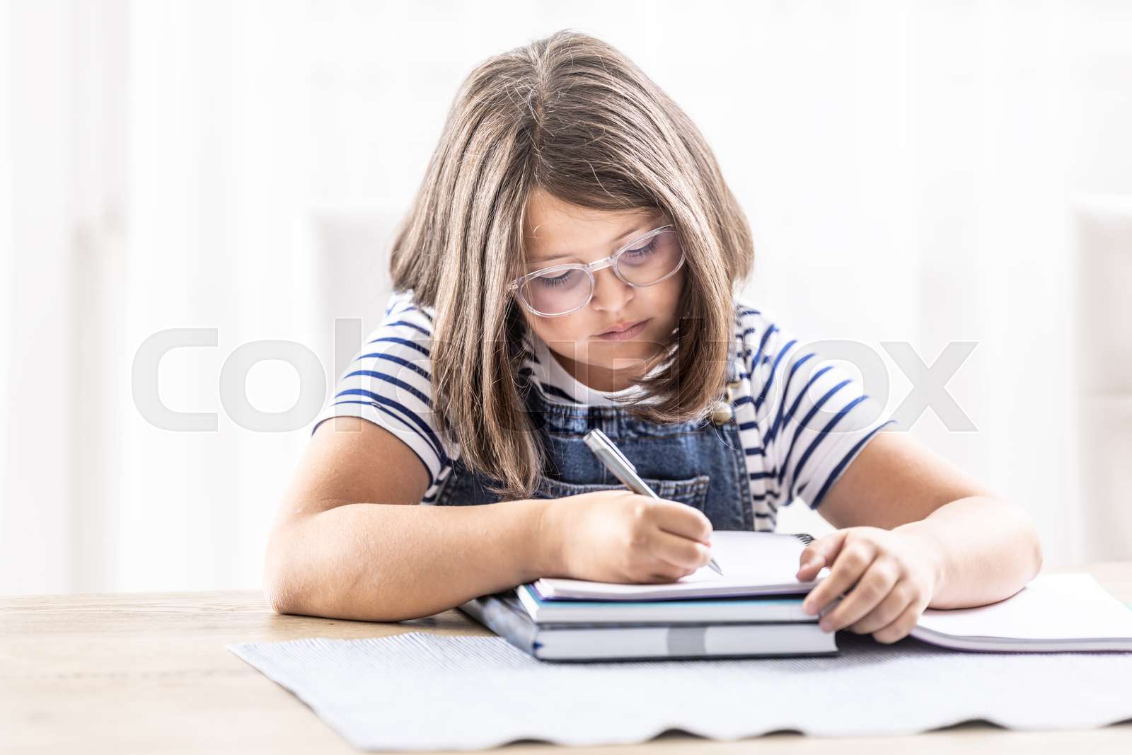 bored-girl-writes-homework-into-an-exercise-book-stock-image-colourbox