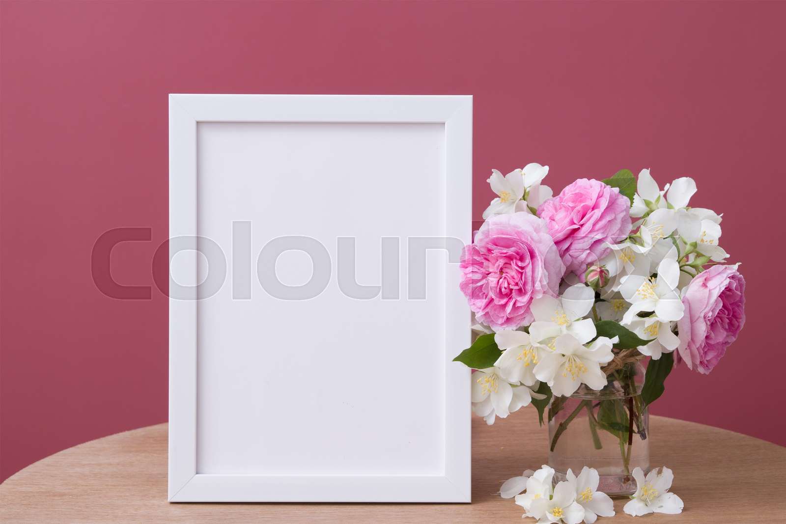 Empty white frame mock up with flowers on pink background. Temlate for your text or picture