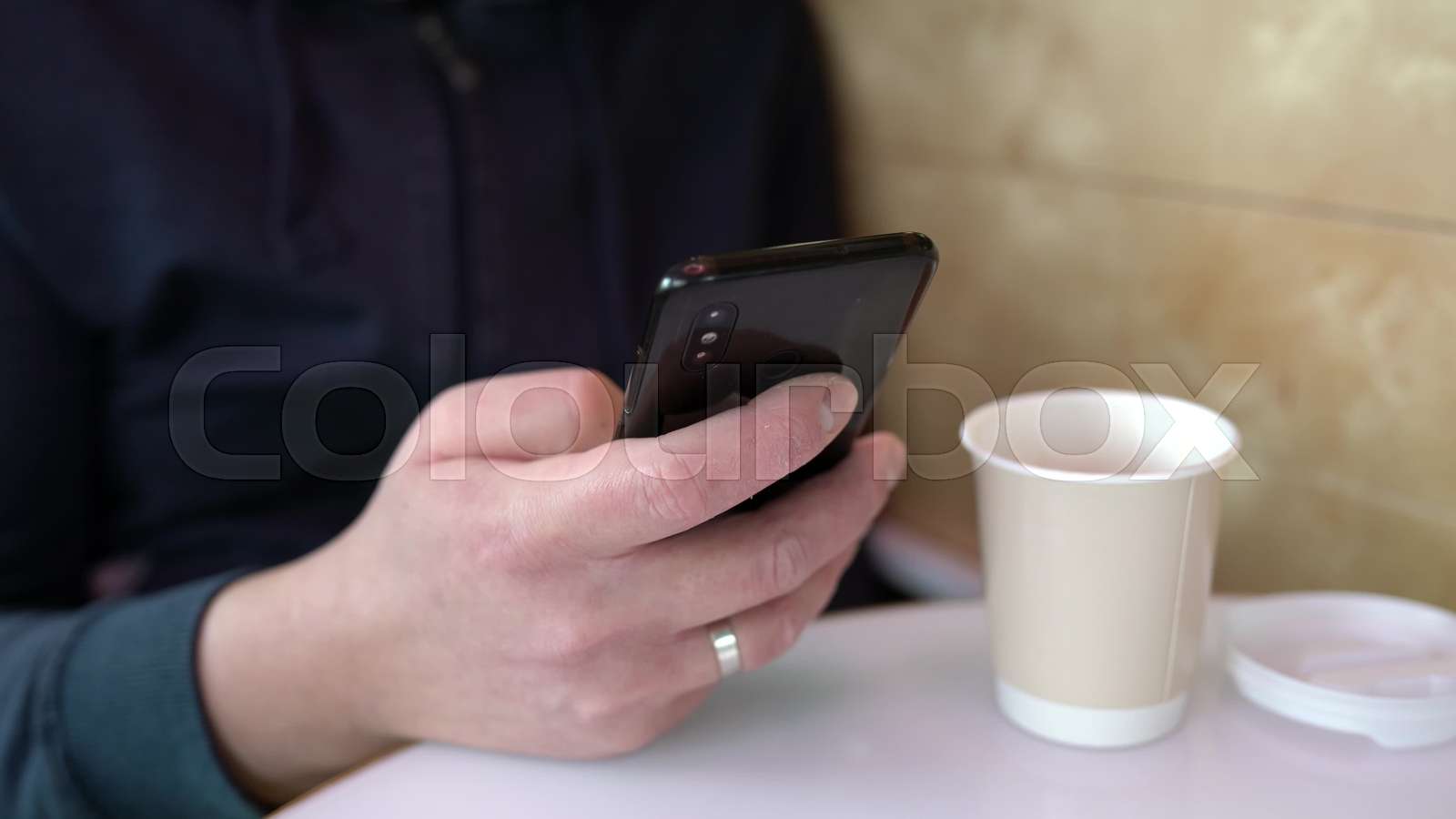 Businessman using phone at coffee shop typing a text message closeup. A
