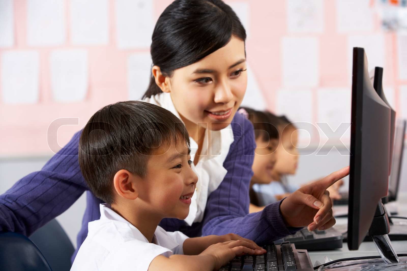 Teacher Helping Student During Computer Class In Chinese School Teacher Helping Student During Computer Class In Chinese School