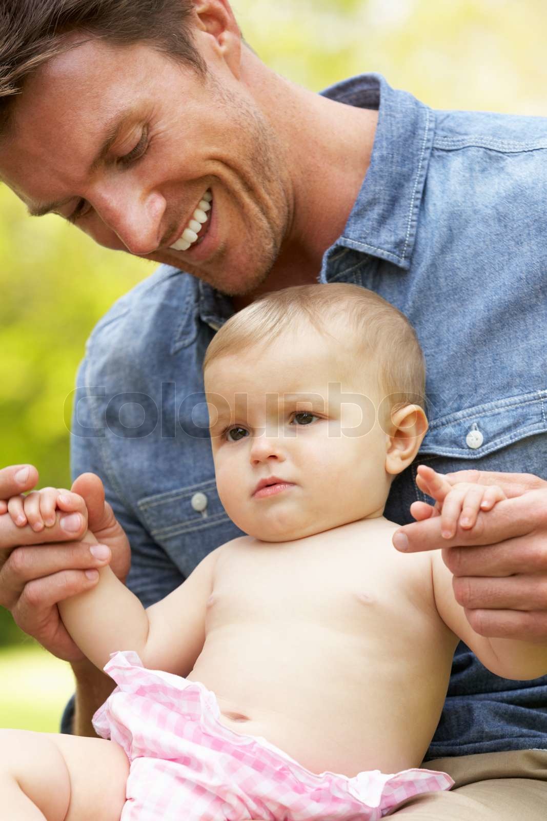 Father Sitting With Baby Girl In Field Of Summer Flowers Stock Image