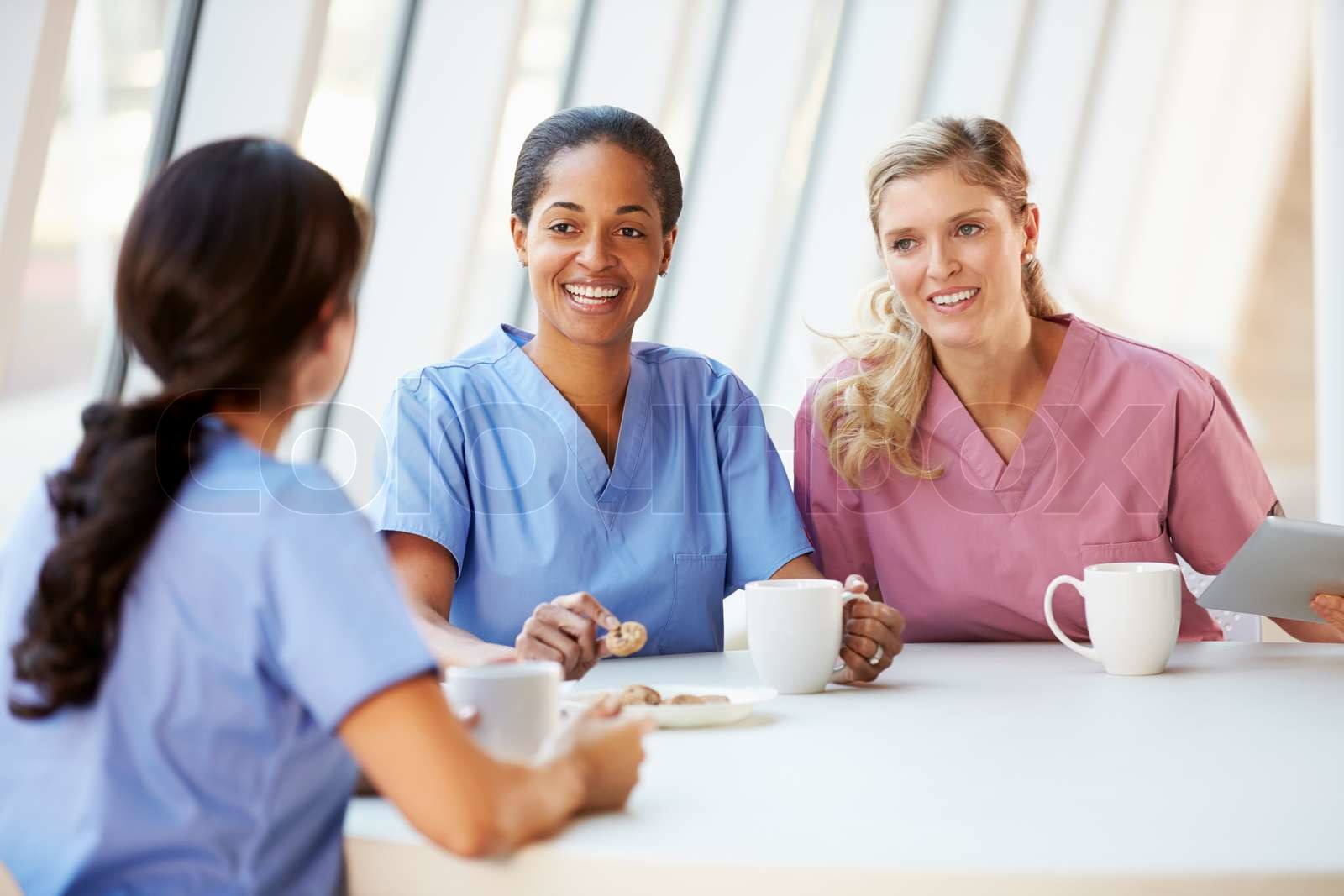 Group Of Nurses Chatting In Modern Hospital Canteen Stock image