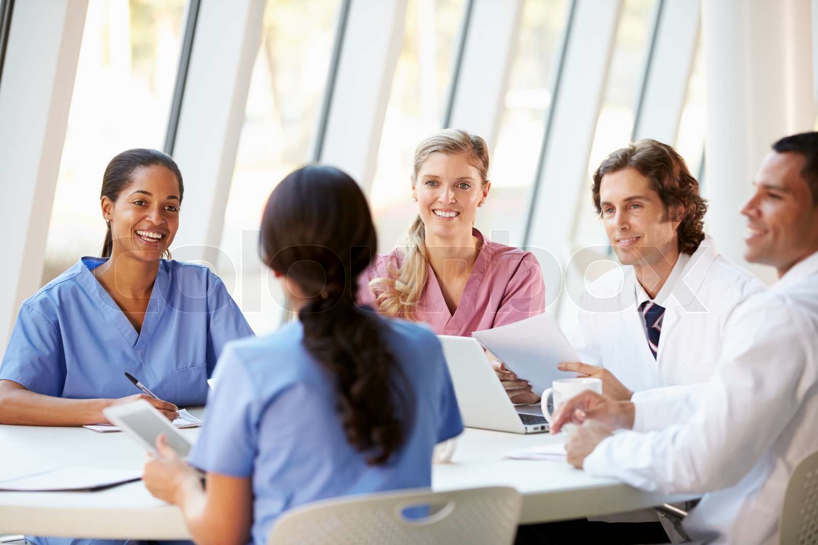 Medical team meeting around table in modern hospital stock image