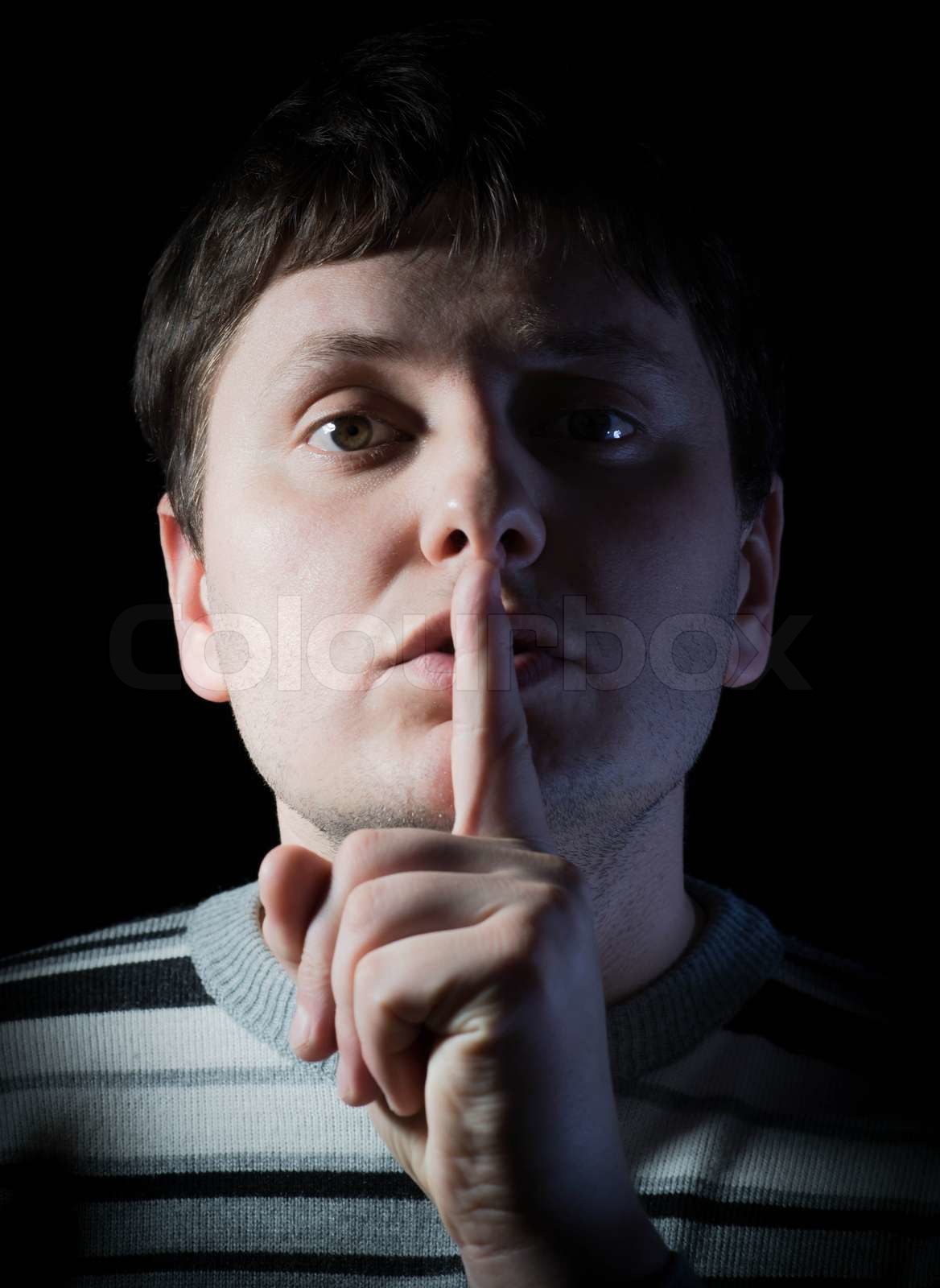 Junger Mann mit Finger auf die Lippen Stock Bild Colourbox