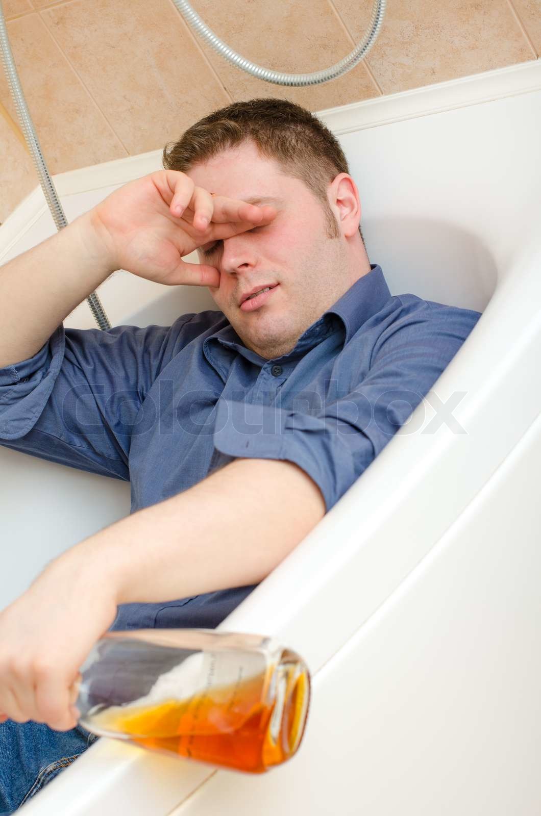 Drunk man with bottle lying in bath Stock image Colourbox