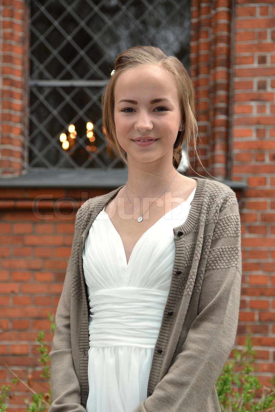 Smiling Caucasian Girl With White Dress In Front Of Red Building