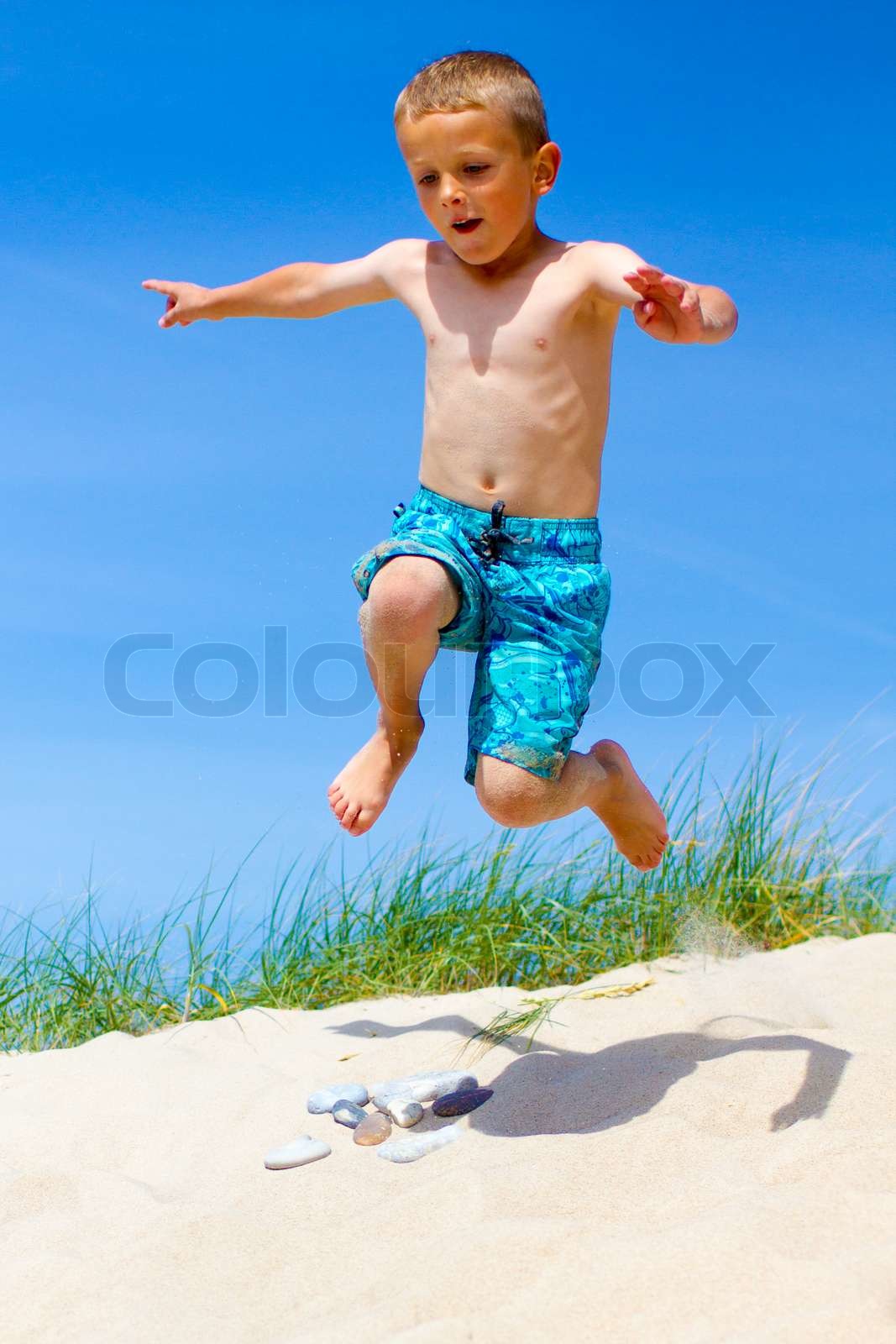 Boy jumping from a sand dune Stock image Colourbox