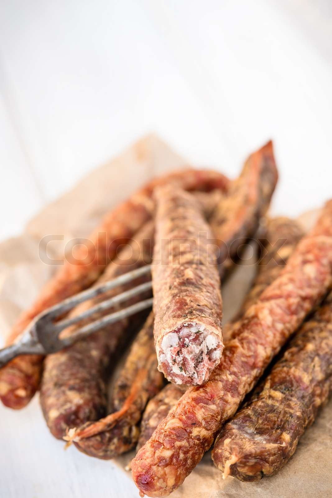 Heap of traditional air dried german sausages with a rustic fork