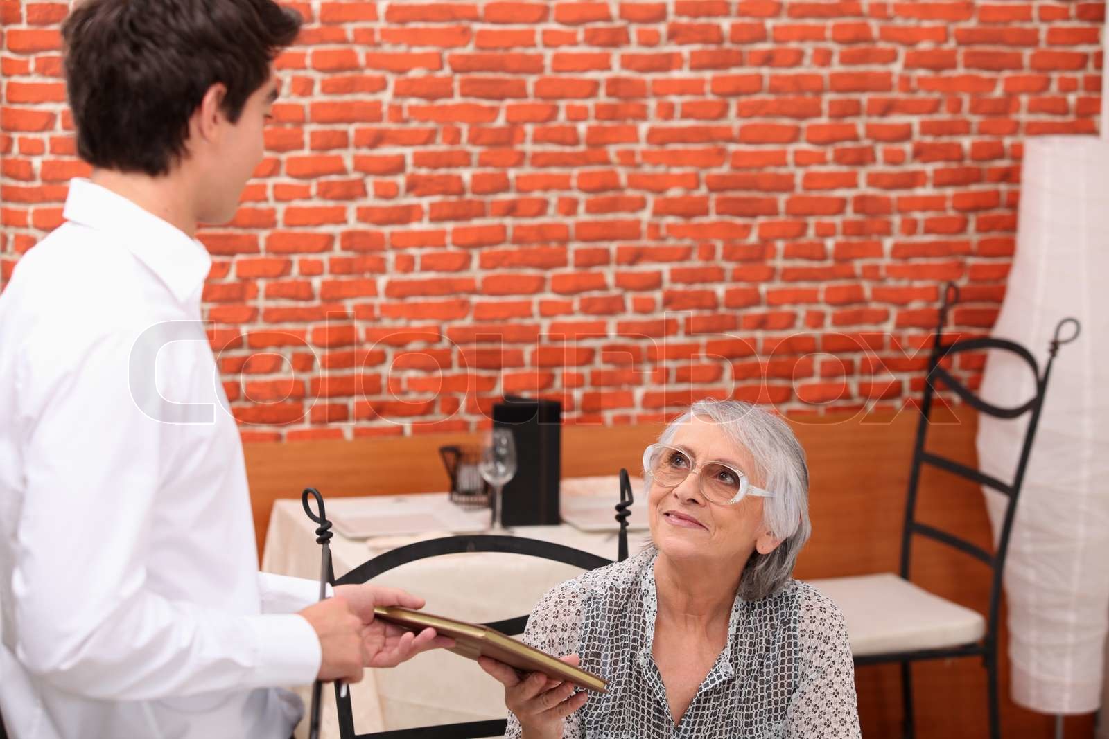 Man handing menu to old lady | Stock image | Colourbox